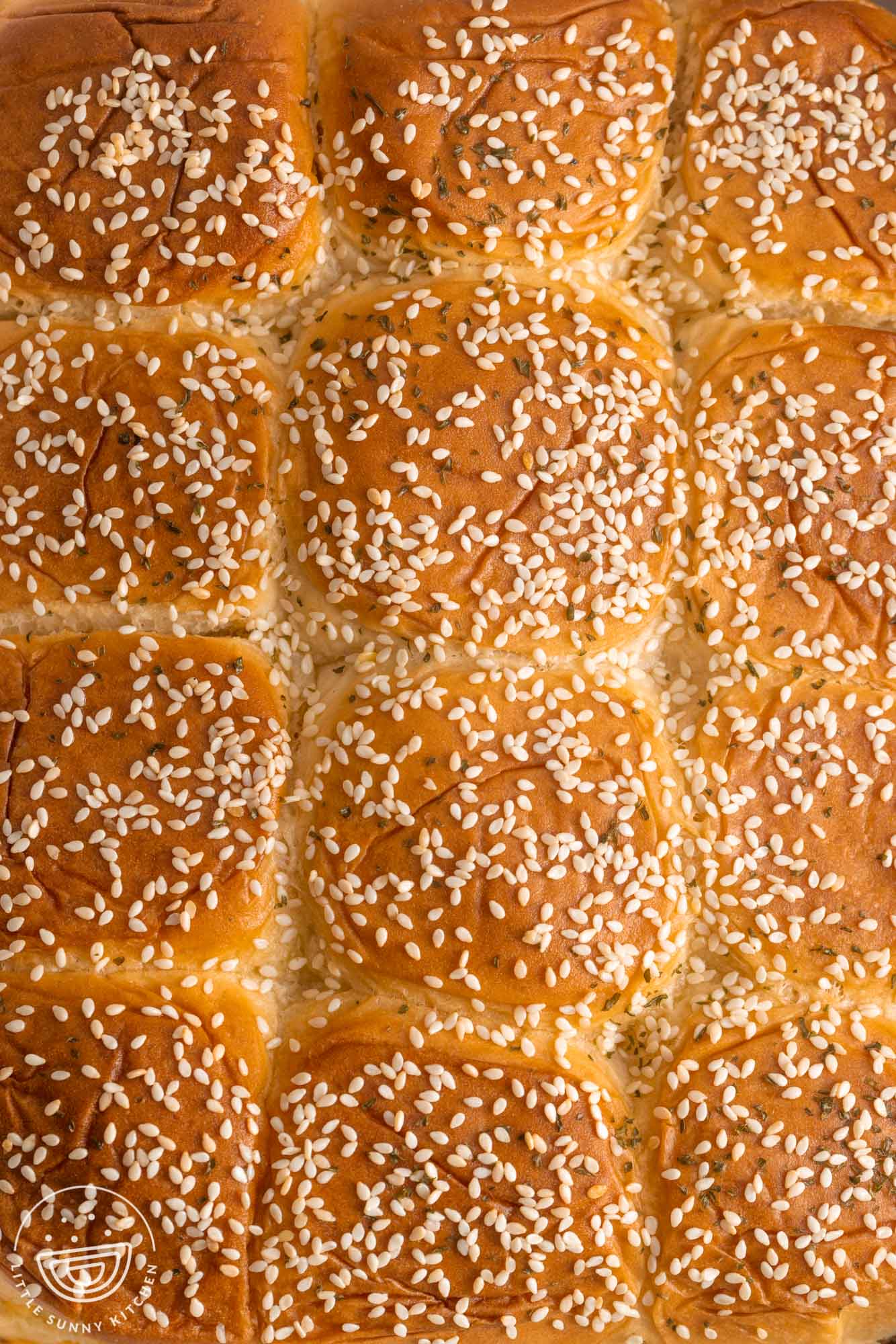 A full tray of Hawaiian rolls topped with sesame seeds for making sliders.