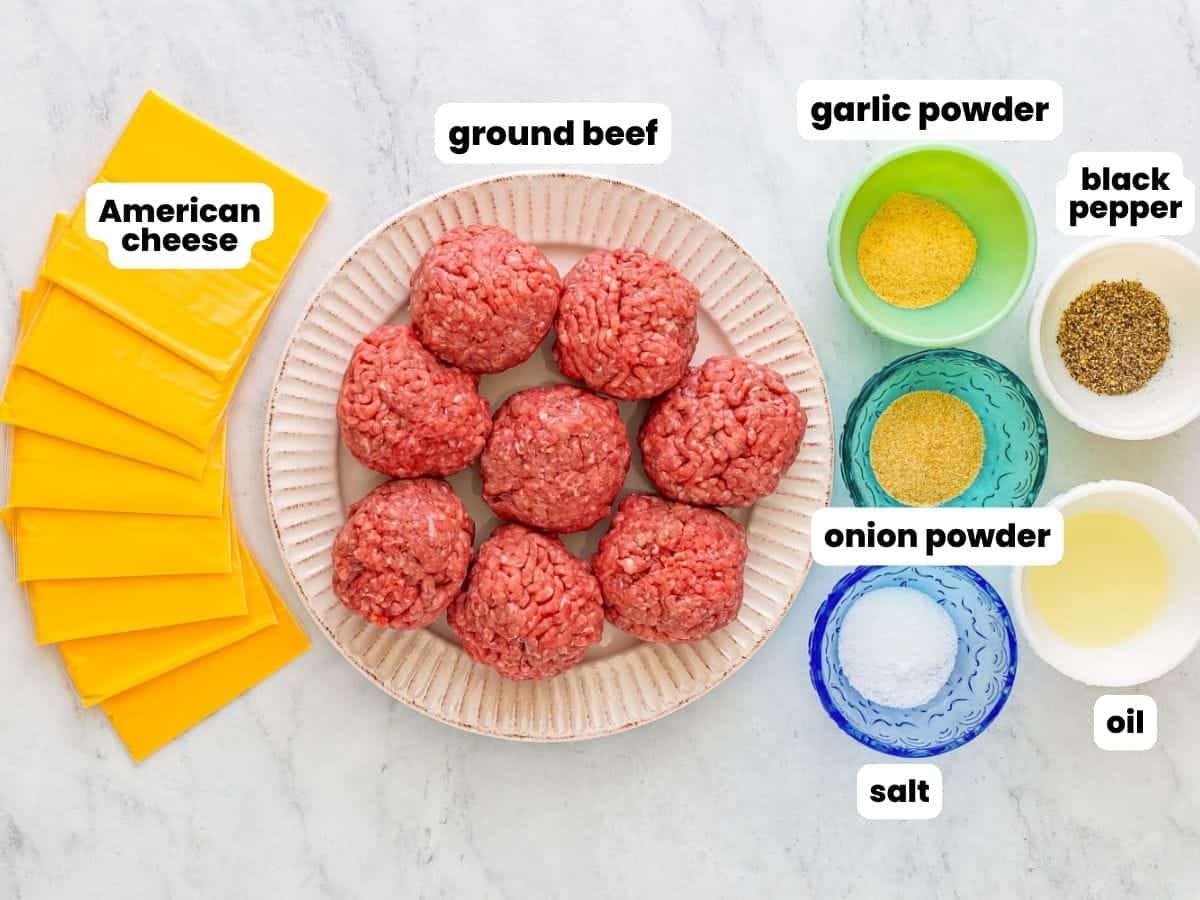 a plate of ground beef rolled into balls, with seasonings in small bowls and slices of American cheese.