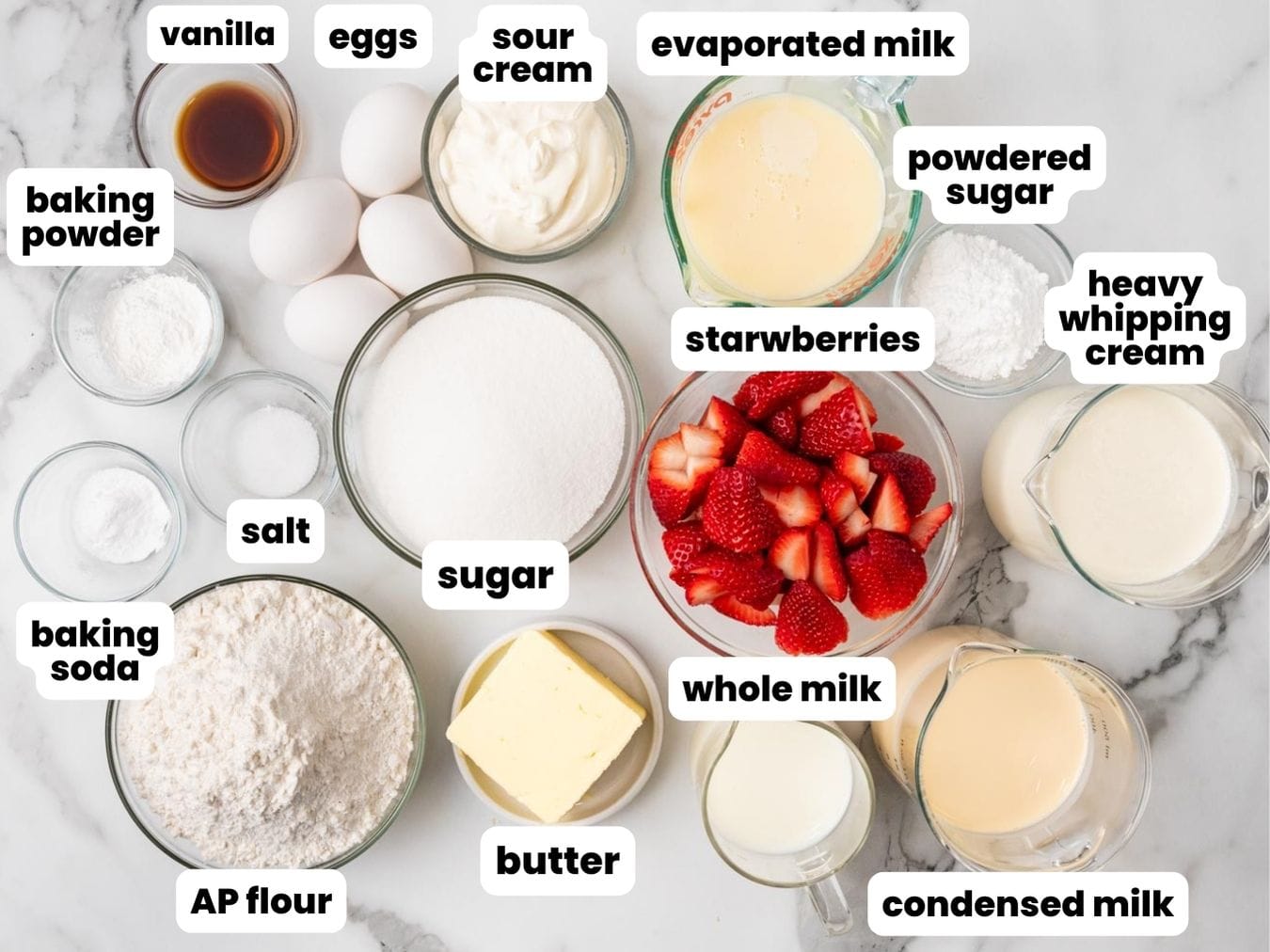 the ingredients needed to make a strawberry cake with tres leches, all measured into small bowls, arranged on a counter. 
