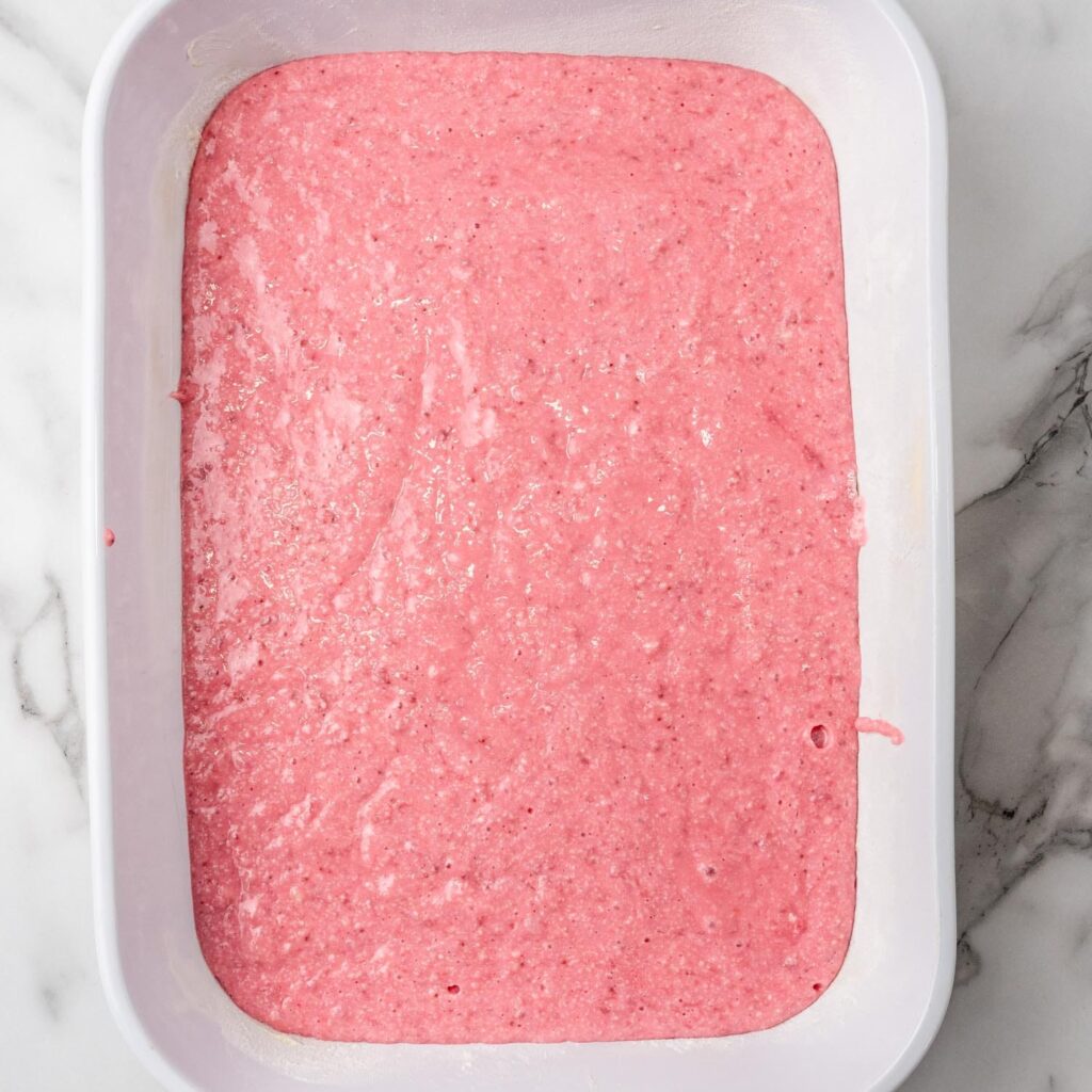 strawberry cake batter in a white 9x13-inch baking dish, viewed from above. 