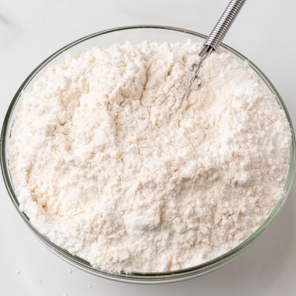 flour in a glass bowl with a whisk.