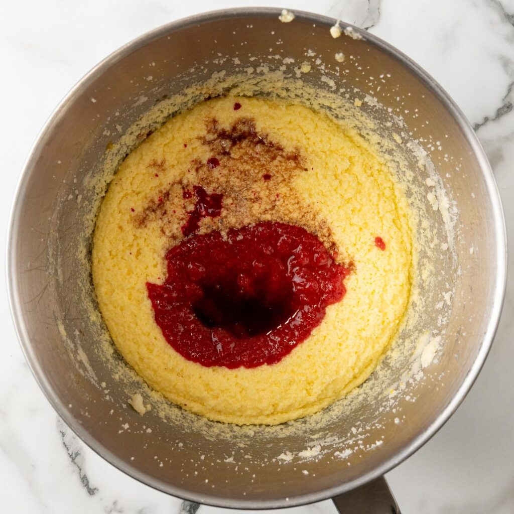 strawberry puree added to cake batter in a metal mixing bowl