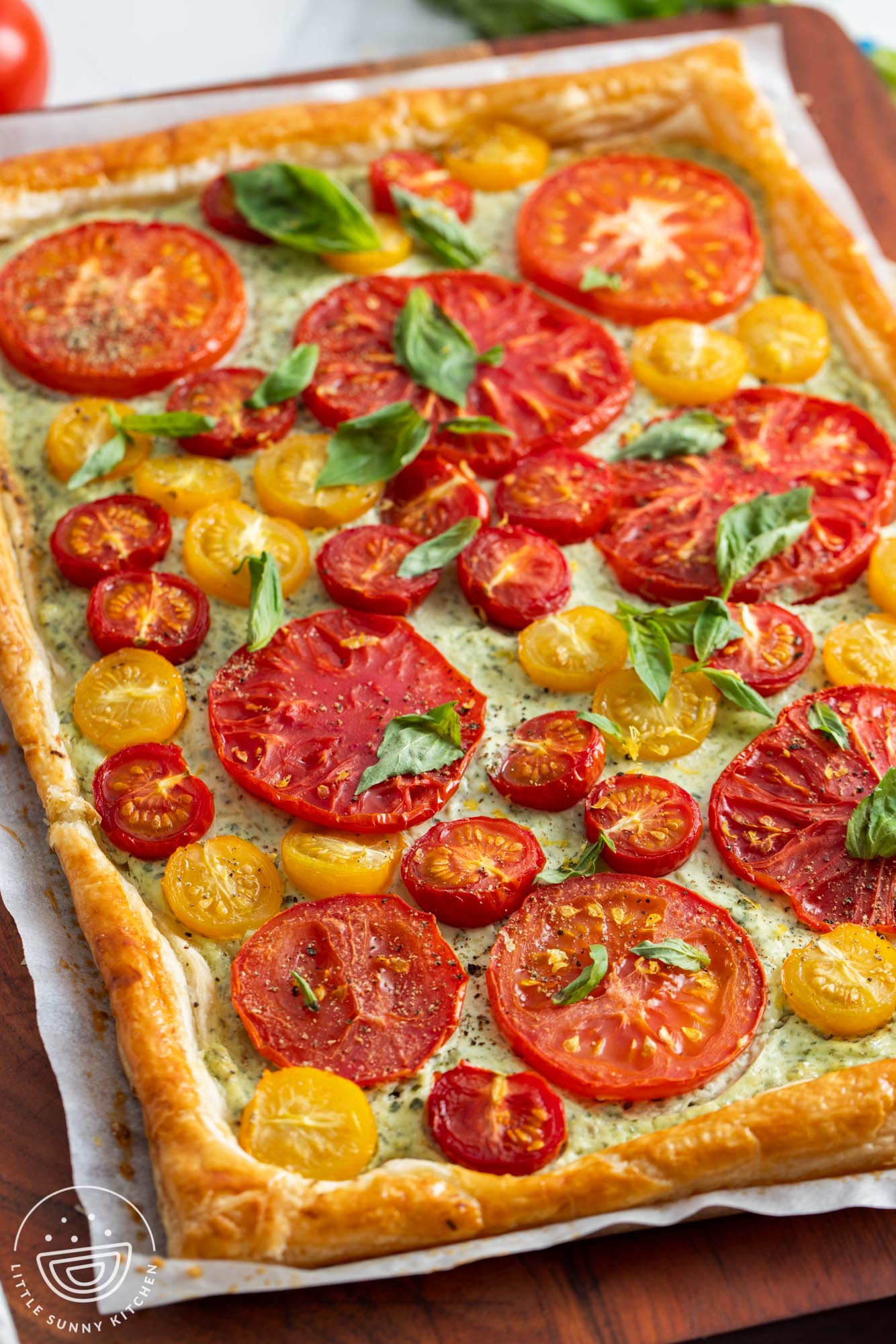 a homemade pastry tart with fresh sliced tomatoes and basil leaves.