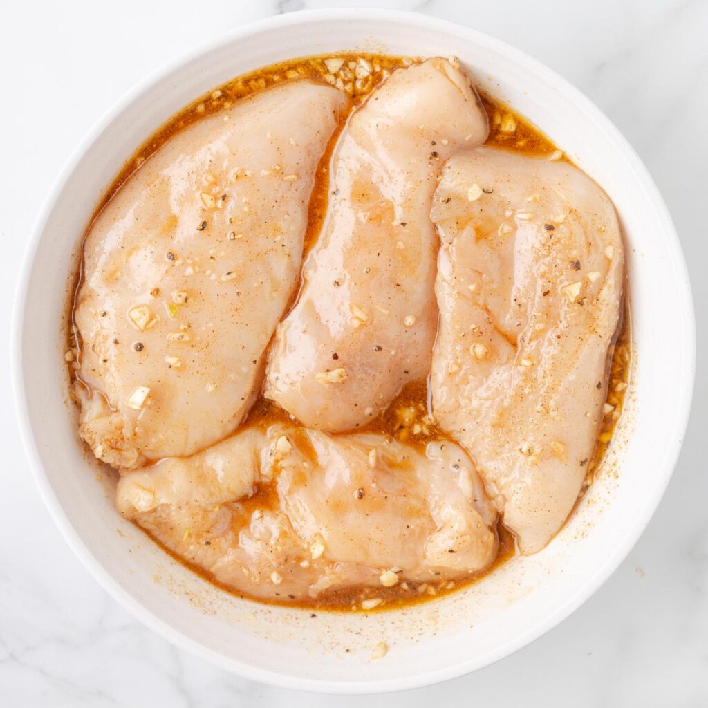 four chicken breasts marinating in a honey lime garlic sauce.