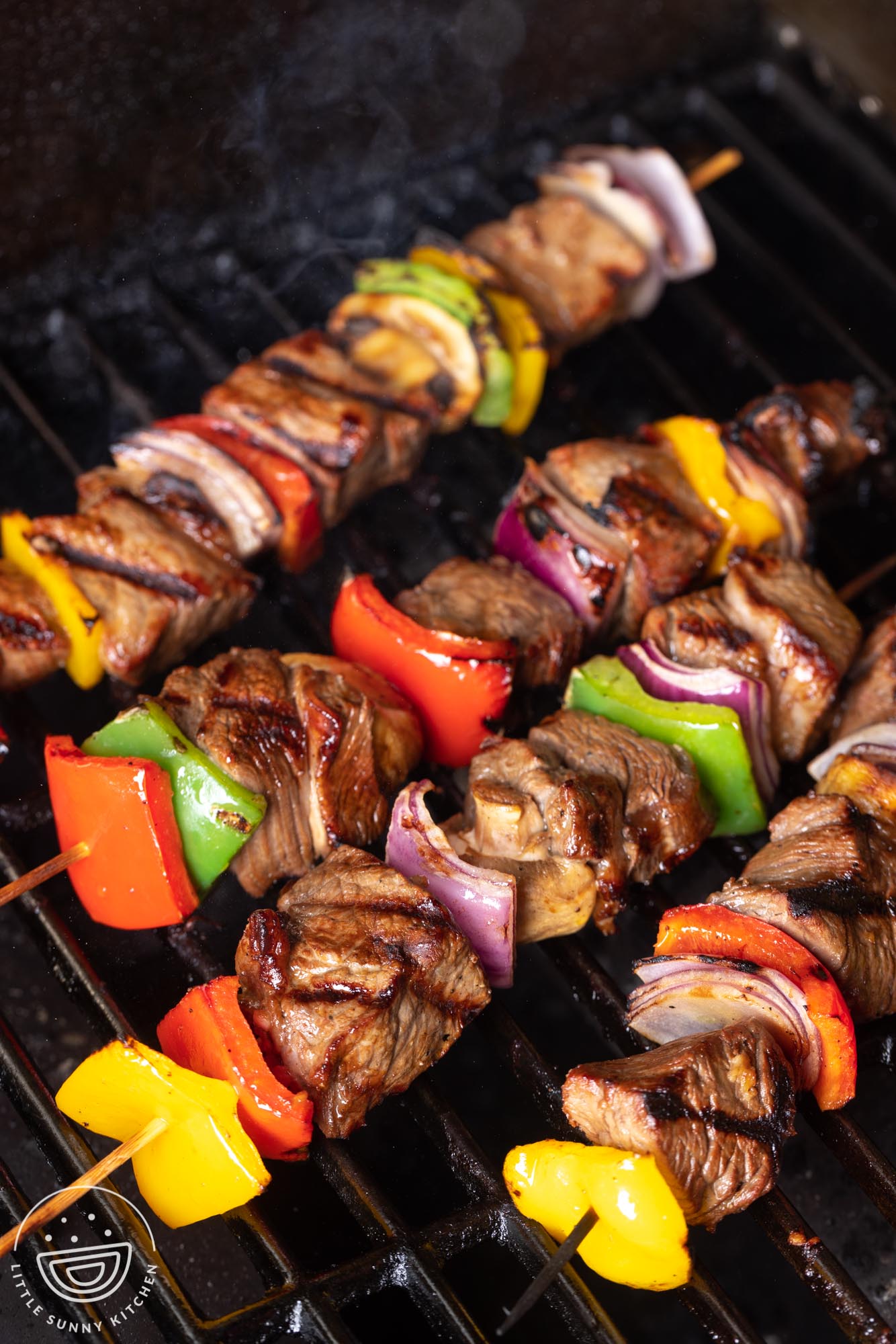 beef kabobs grilling on an outdoor grill.