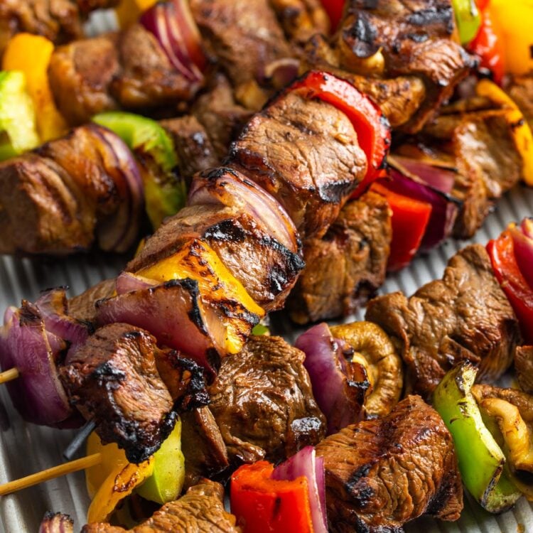 cooked grilled beef kabobs on a metal sheet pan, resting.