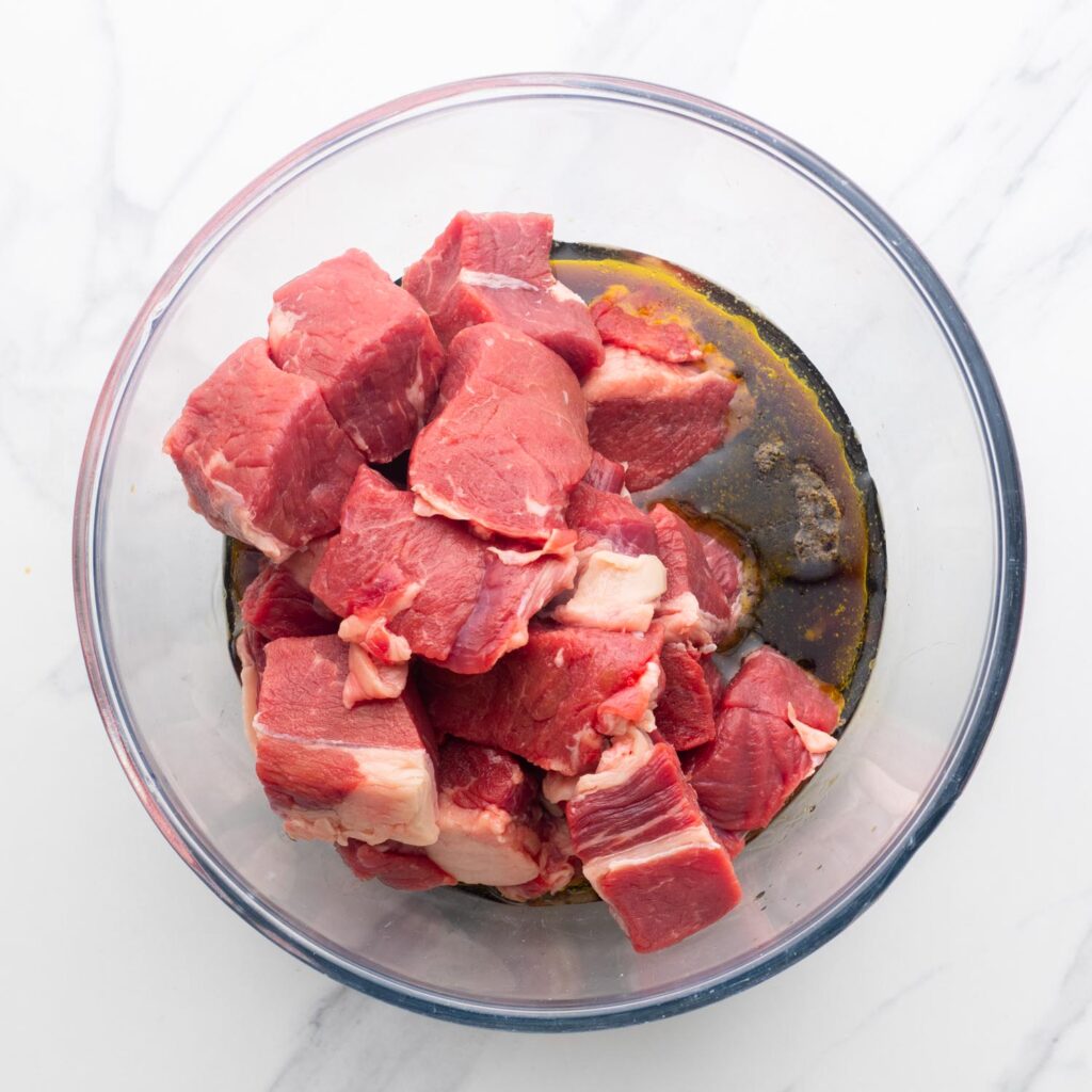 cubes of sirloin steak in a bowl of marinade for kabobs.
