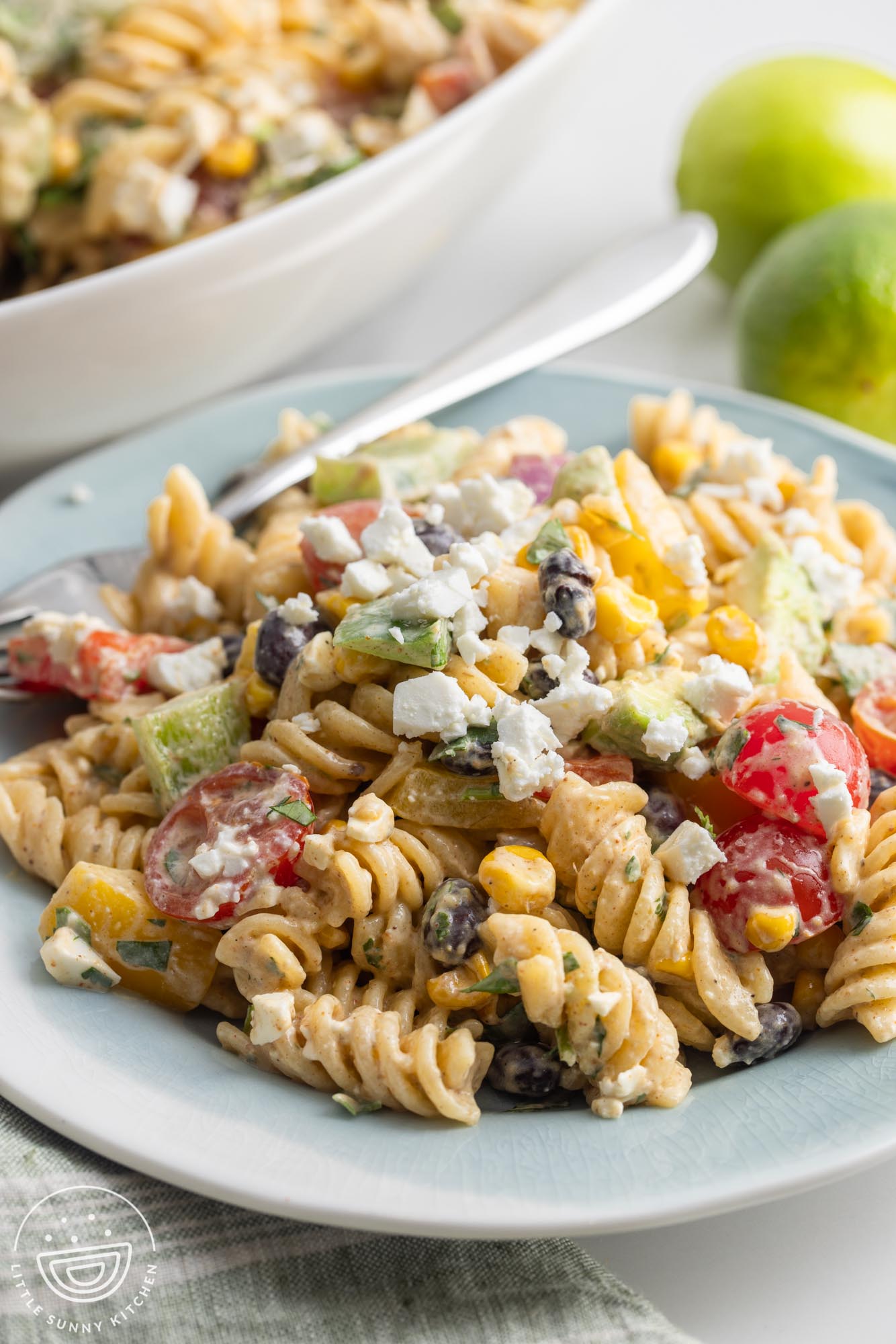 a gray plate holding a generous serving of mexican pasta salad, topped with crumbled cotija cheese.