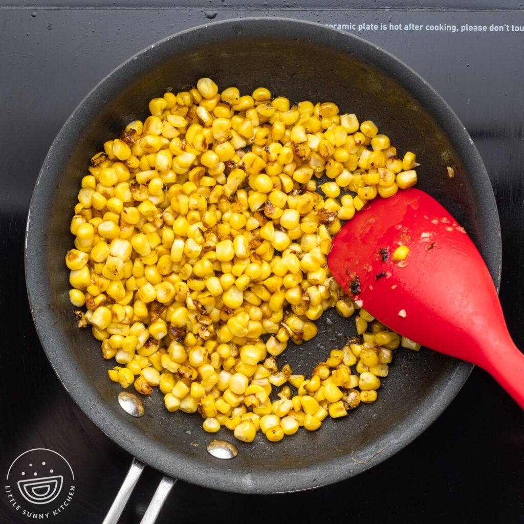 yellow corn kernels grilling in a nonstick skillet over an electric burner.