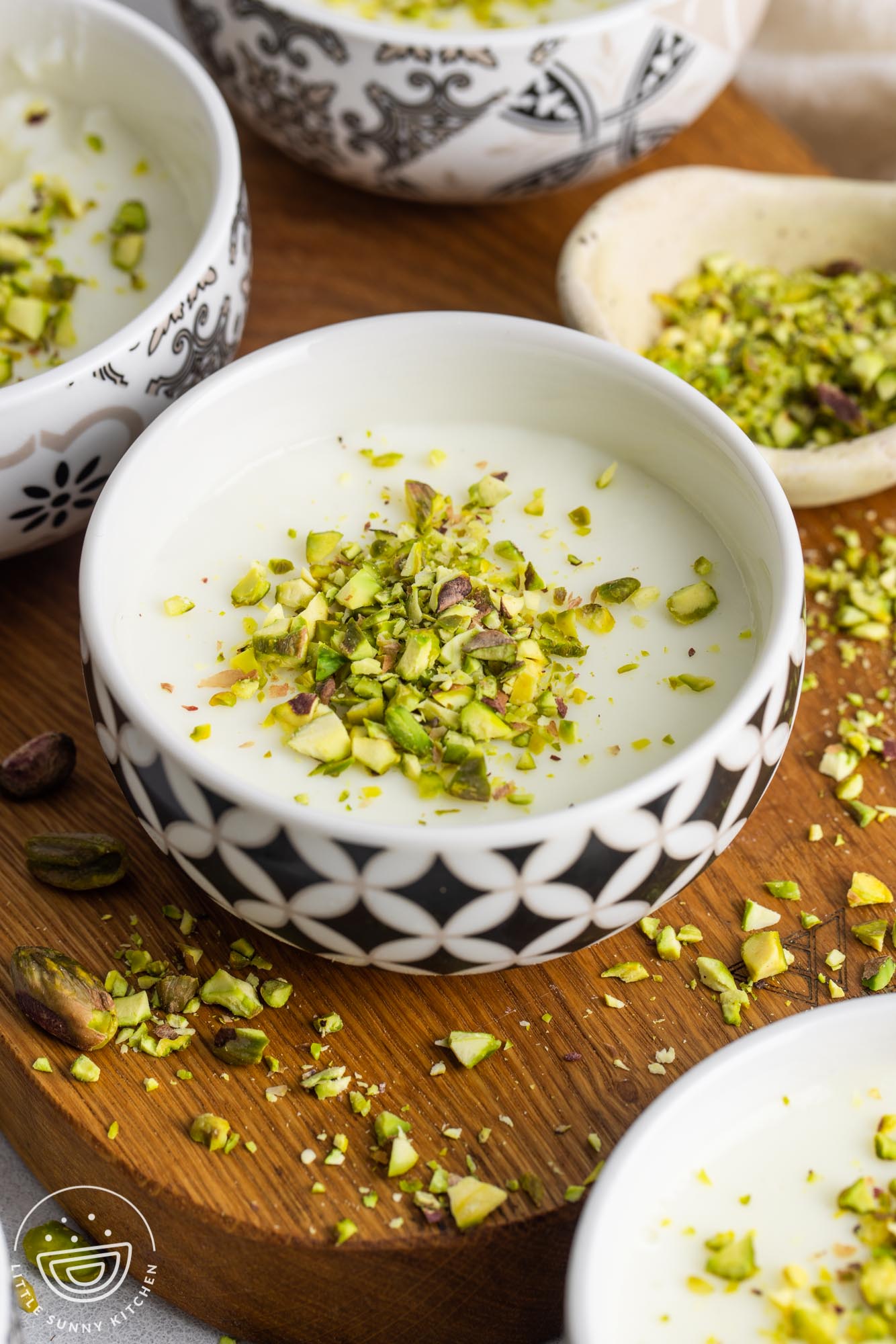 Mouhalabieh served in small white bowls, garnished with crushed pistachios