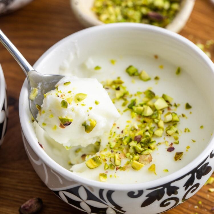 Mouhalabieh served in a small oriental style bowl, with a spoon. Garnished with crushed pistachio