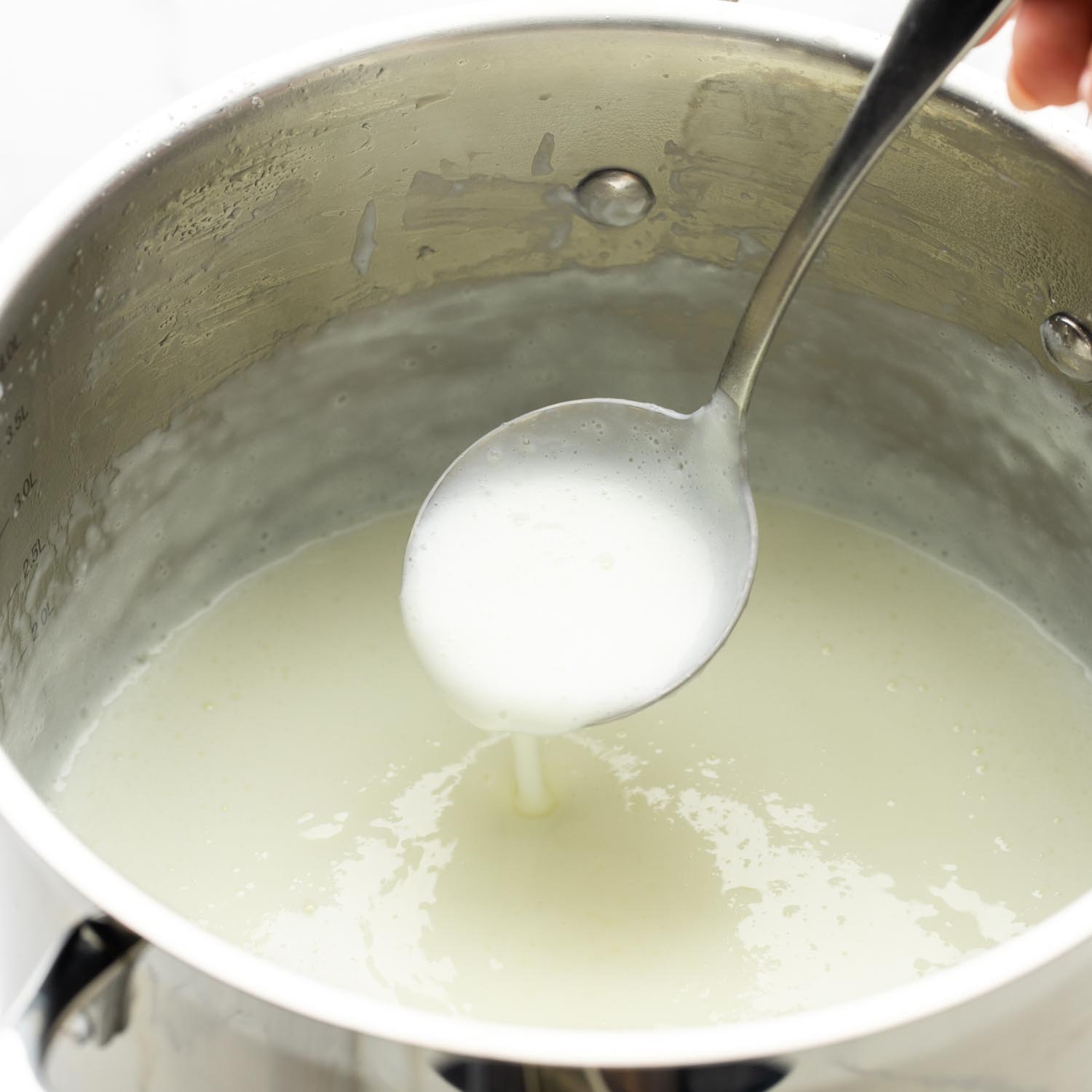 Mouhalabieh in a large pot, being ladled with a stainless steel ladle