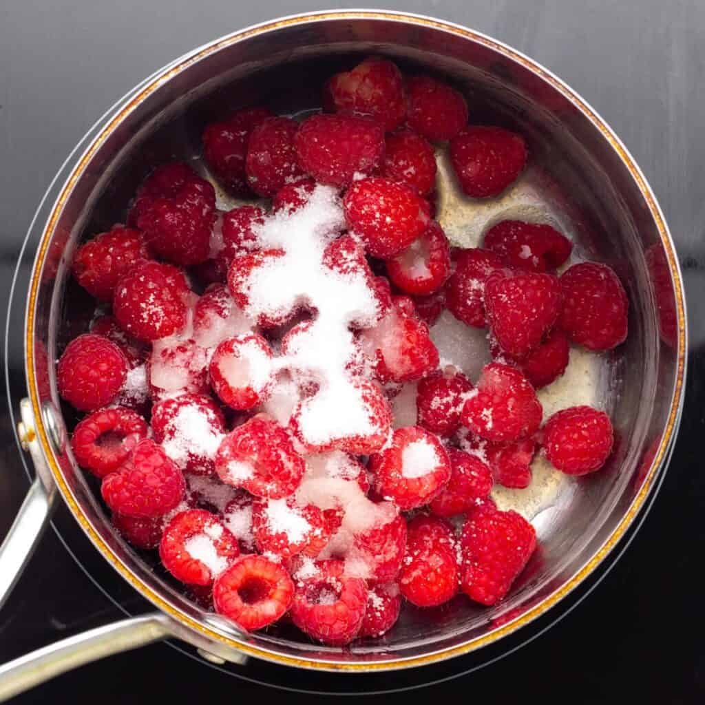 raspberries with sugar and lemon juice in a small metal saucepan.