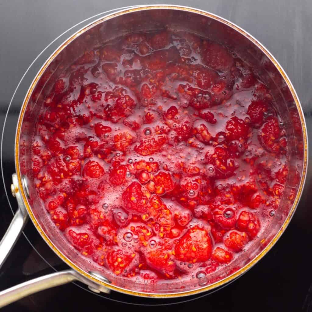 cooked raspberries in a saucepan over an electric burner, viewed from above.