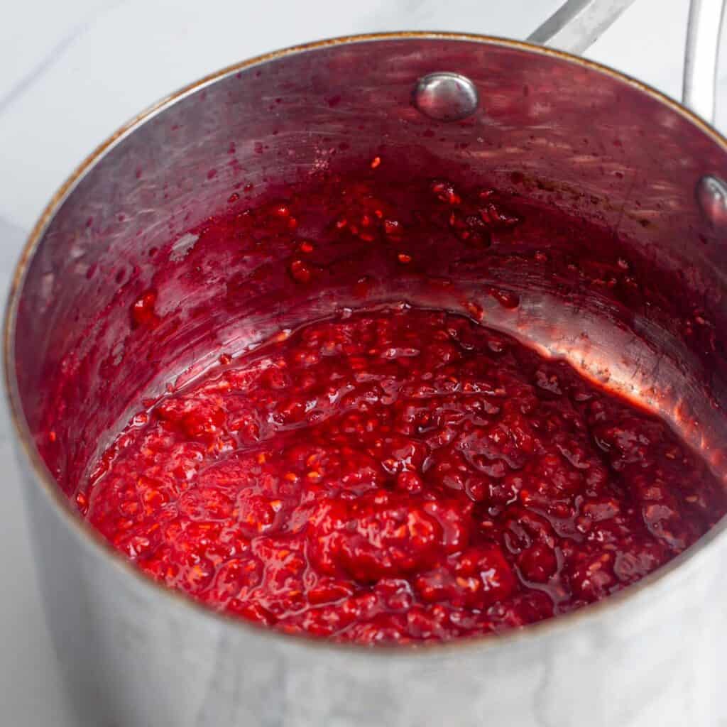 reduced raspberry compote in a metal saucepan.