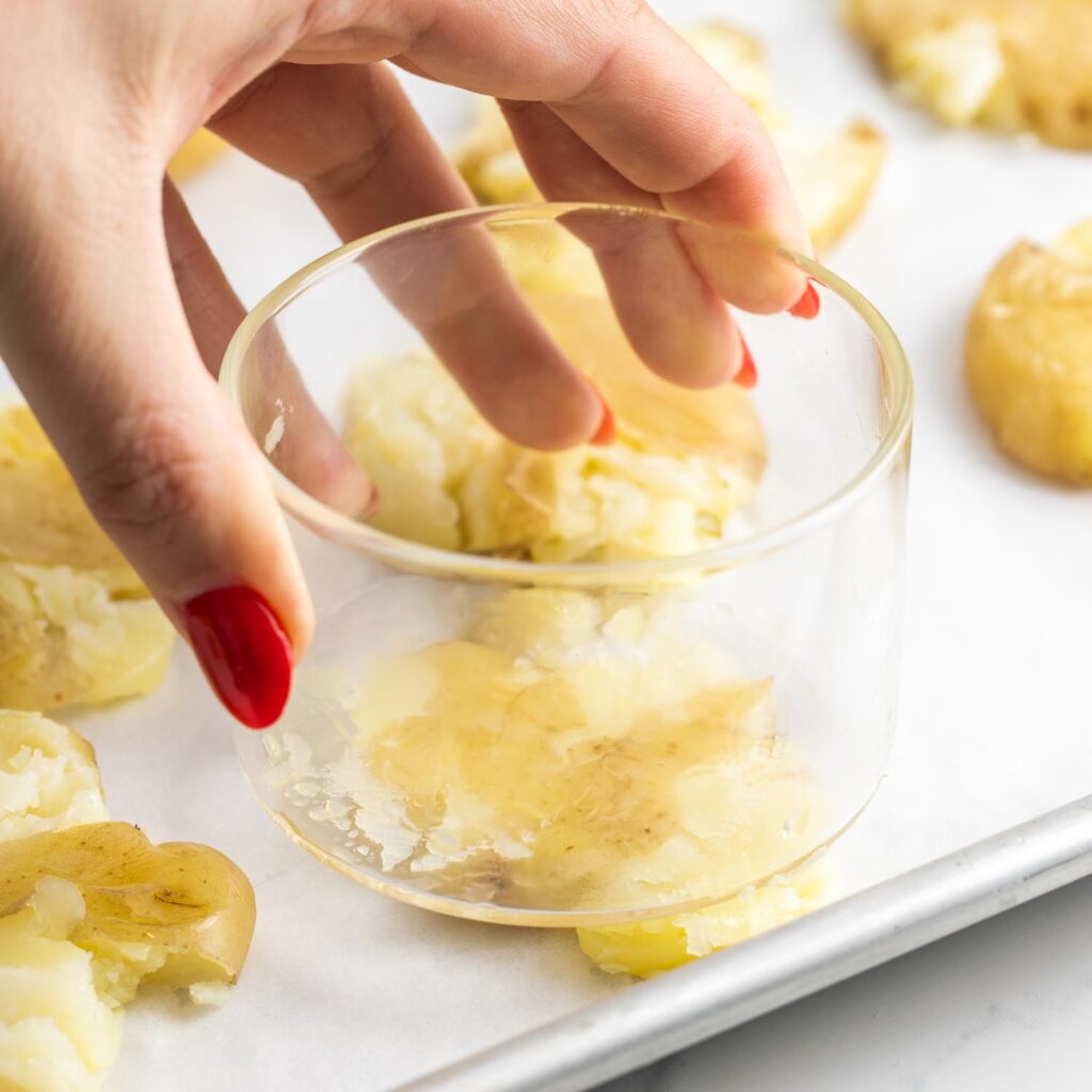 a wide glass pressing down on boiled potatoes to smash them.