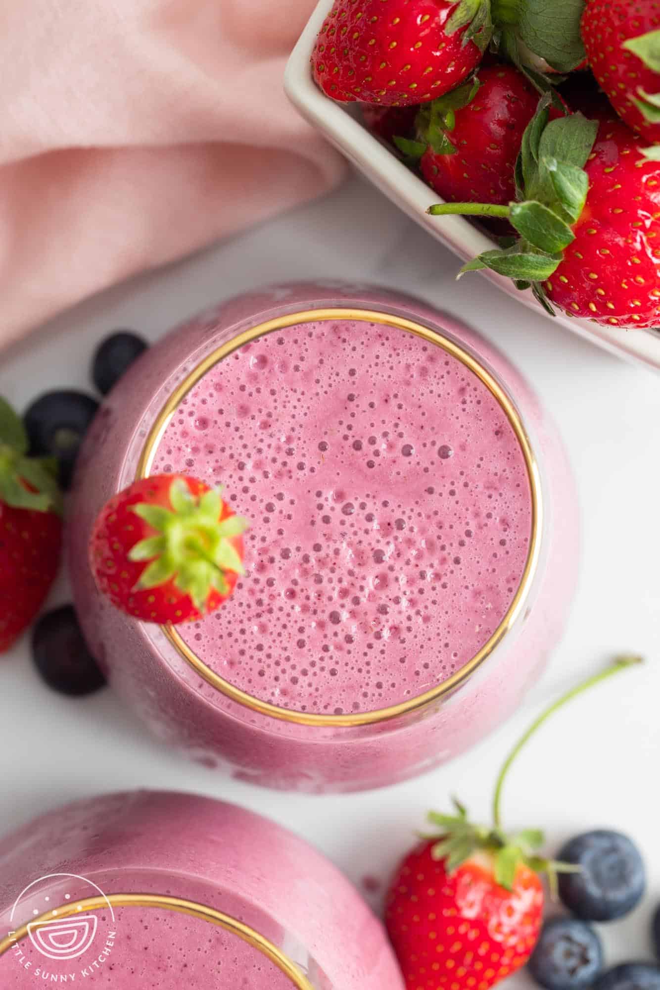 overhead view of a blended strawberry blueberry smoothie in a glass.