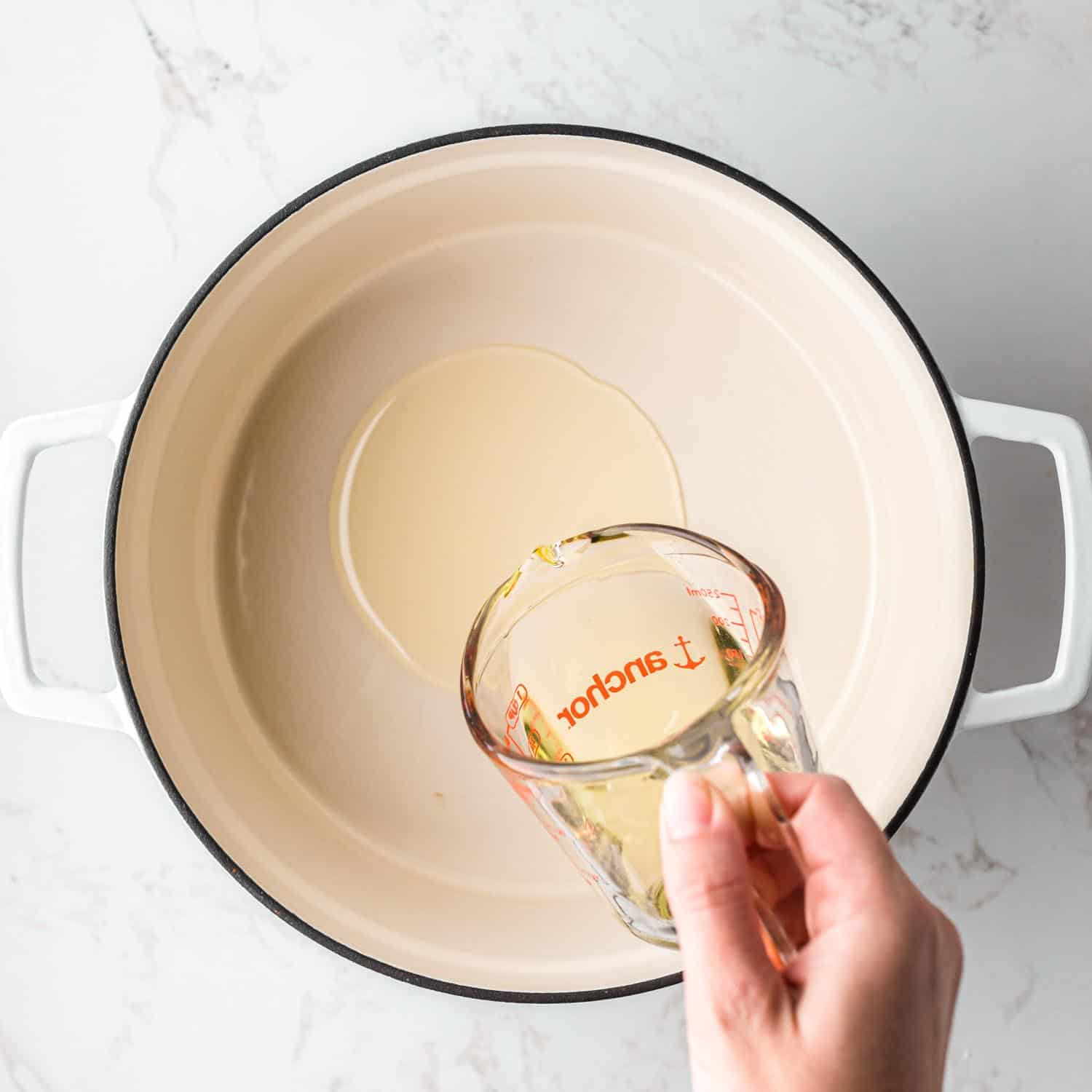 Pouring oil into a white dutch oven