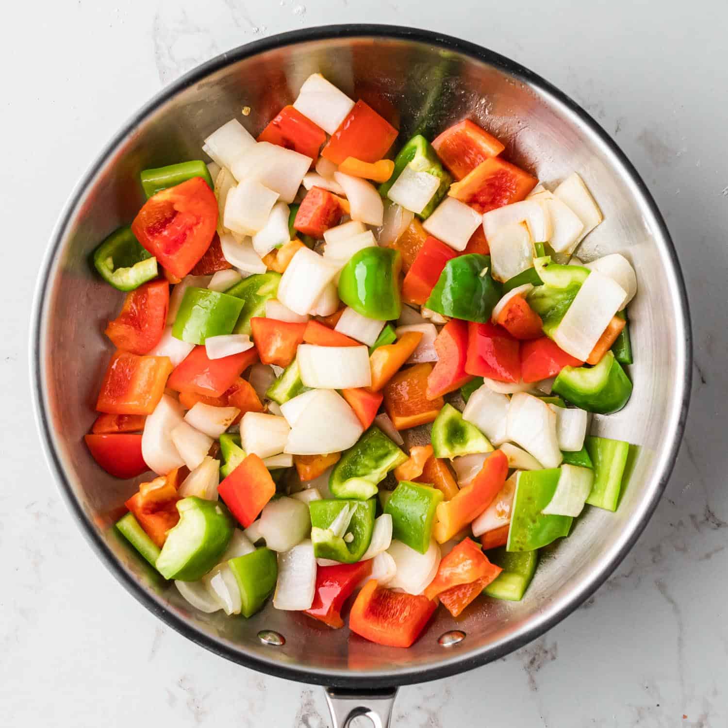 Vegetables in a stainless steel skillet being cooked