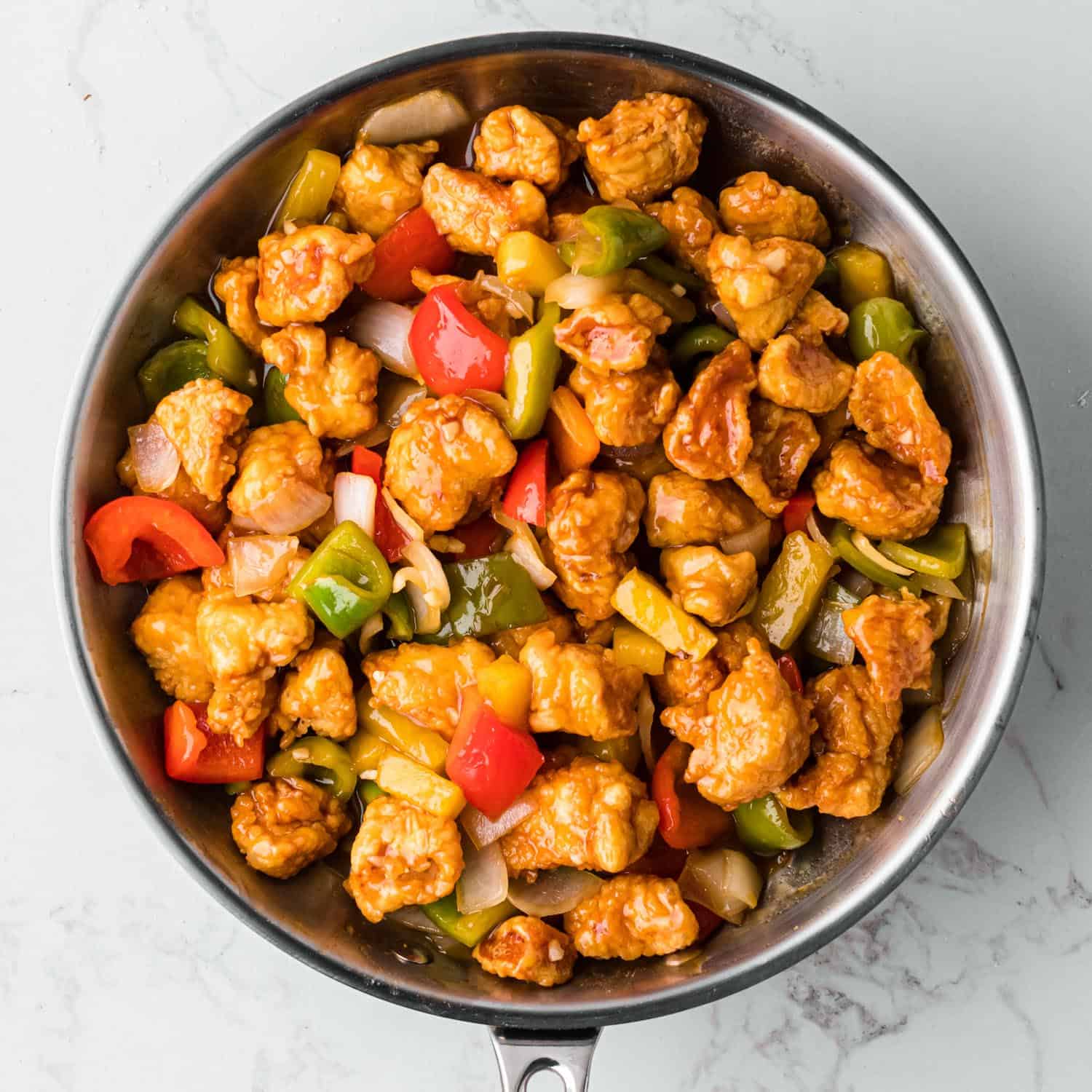 Chicken added to the vegetables and sauce in the skillet to make the final dish of sweet and sour chicken