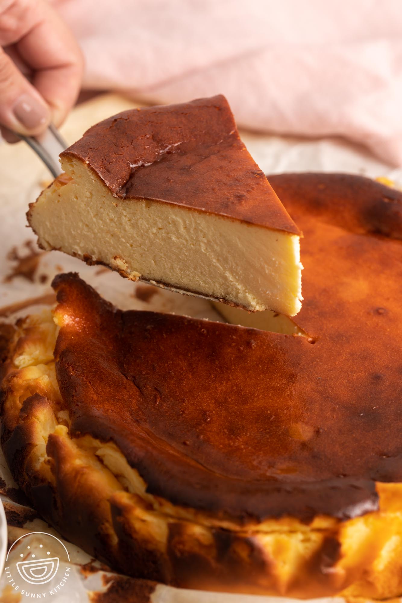 a slice of basque cheesecake lifted from the whole cake with a cake server.