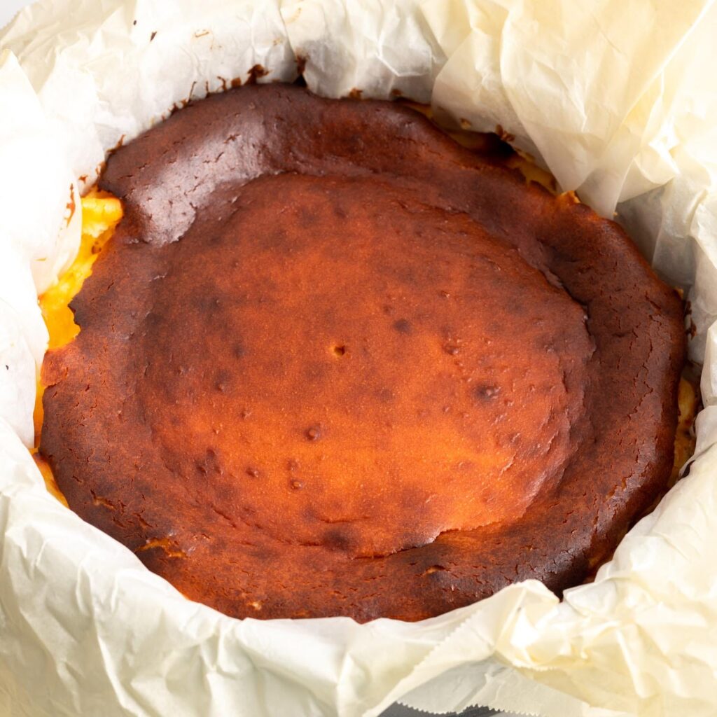 deep golden brown baked basque cheesecake in parchment paper, after cooling.