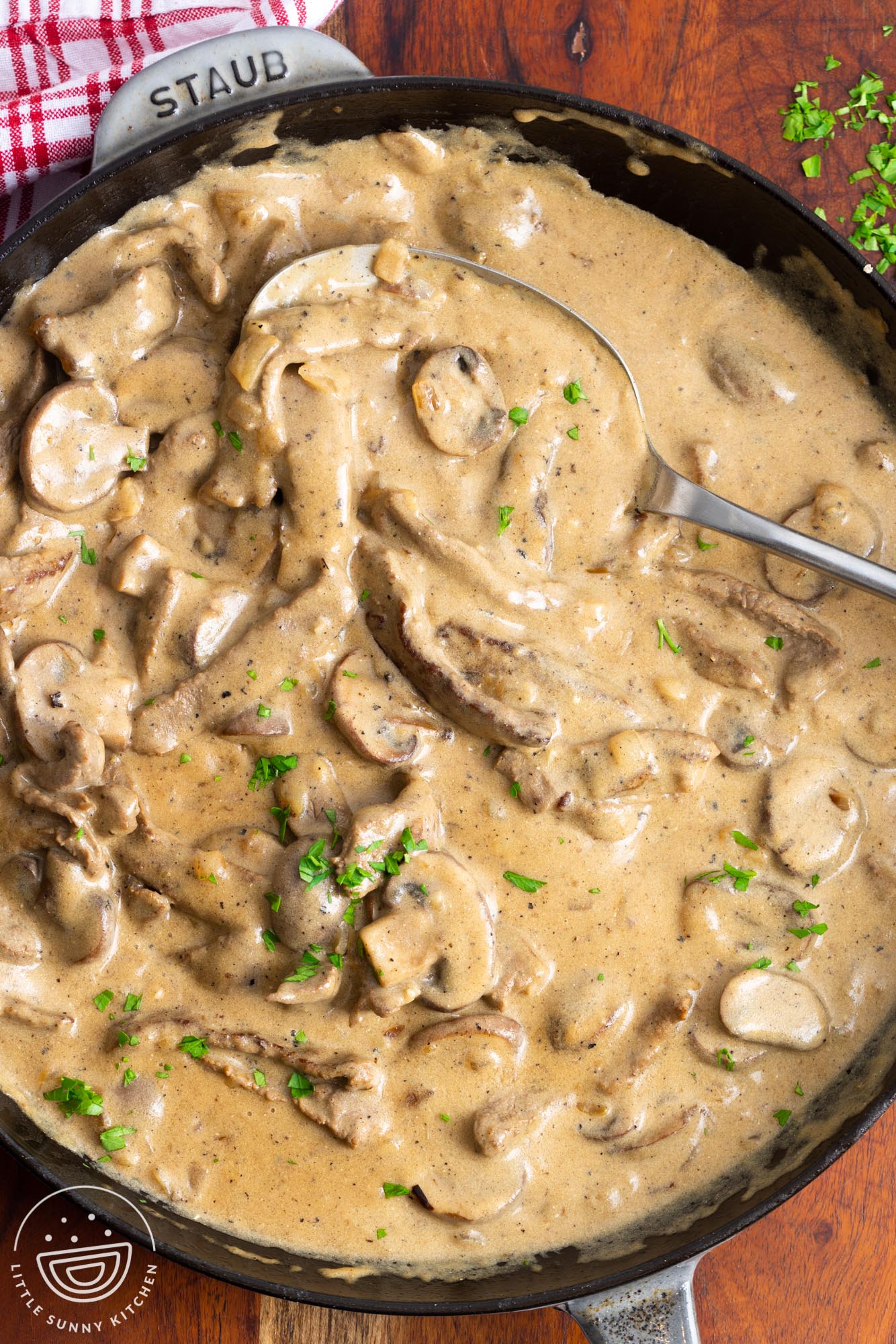 a spoon serving beef stroganoff from a skillet.