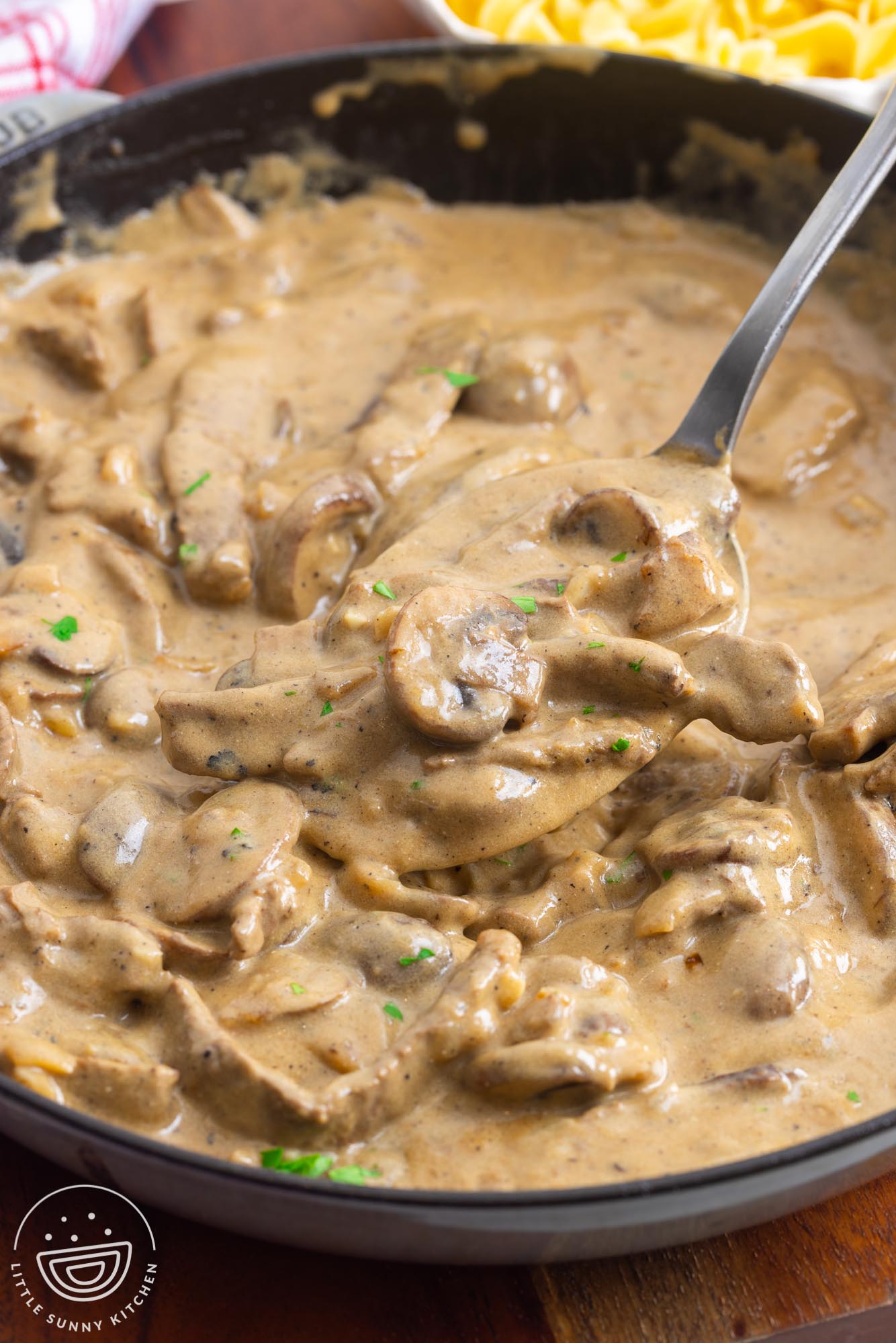 creamy beef stroganoff with mushrooms, served with a large metal spoon.