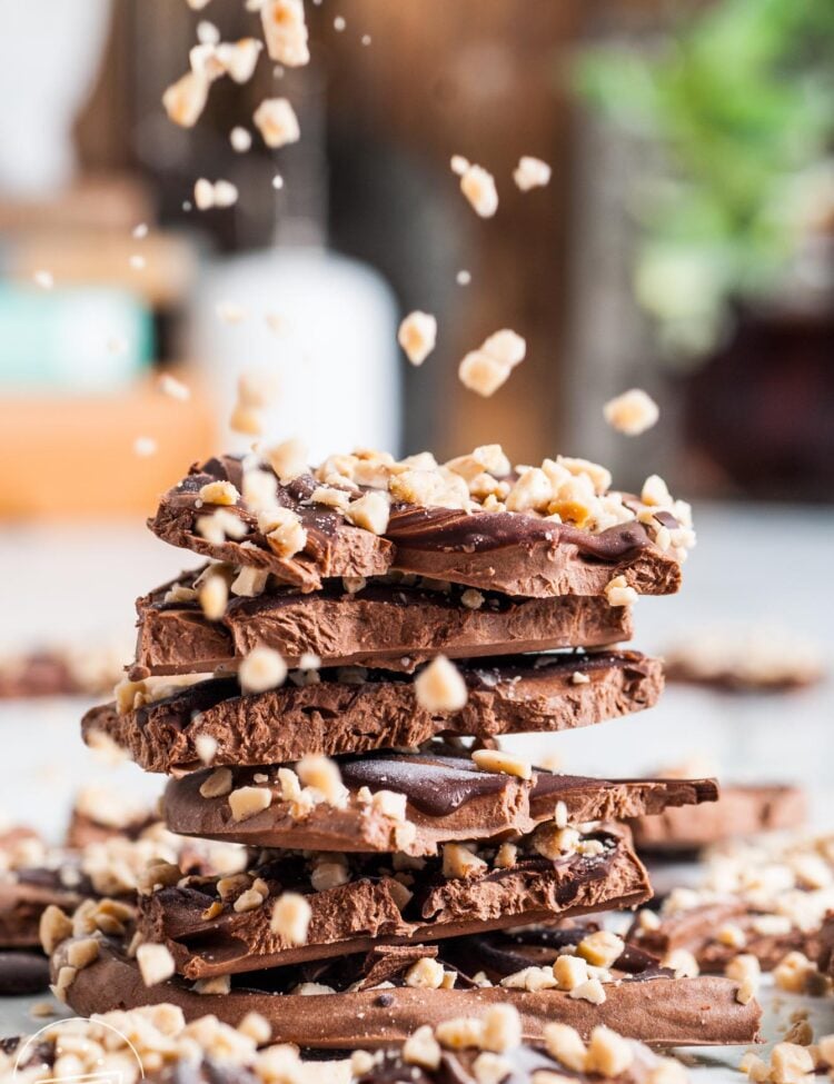 a stack of chocolate frozen yogurt bark pieces. Toffee bits are being sprinkled over them.