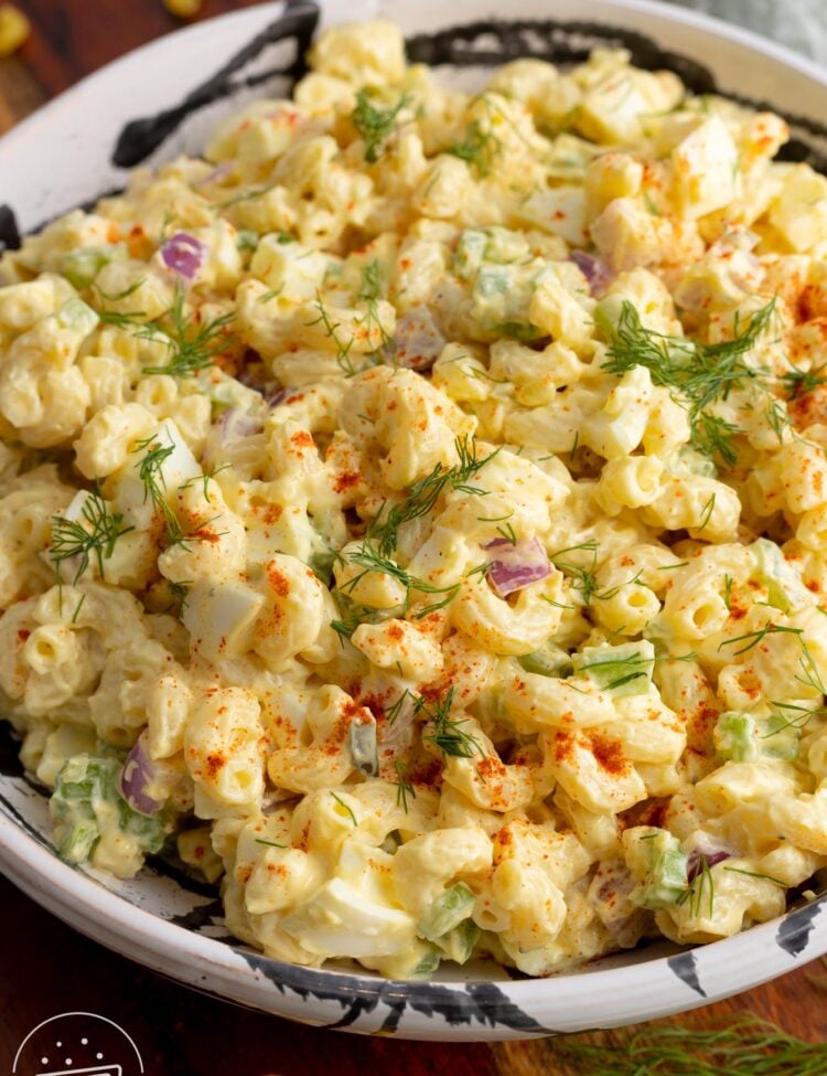 Deviled egg macaroni salad in a large bowl, garnished with dill and paprika.