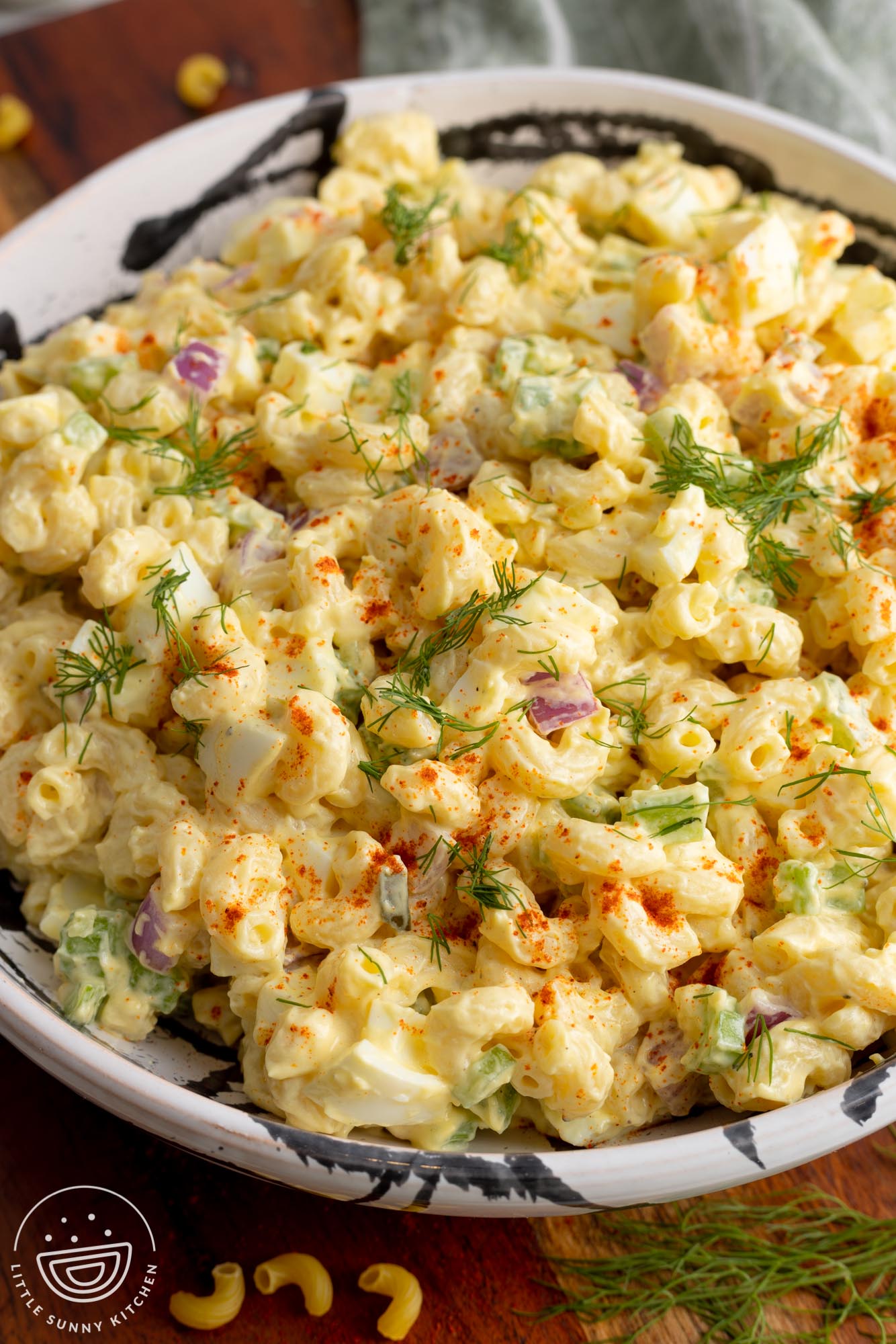 Deviled egg macaroni salad in a large bowl, garnished with dill and paprika.