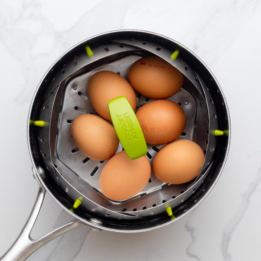 6 brown eggs steaming in a saucepan.