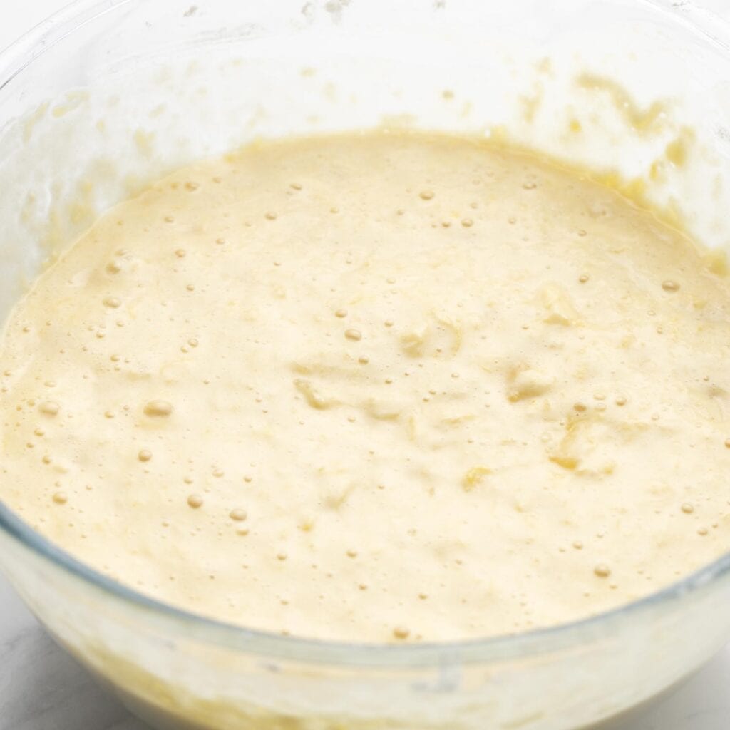 Cake batter for Do Nothing Cake, bubbly in a glass mixing bowl.