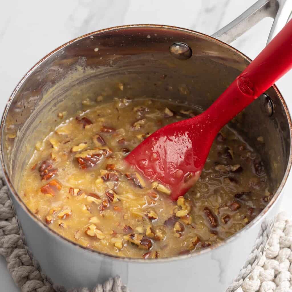 A small saucepan cooking together butter, sugar, coconut, pecans, and evaporated milk to make a frosting for Do Nothing Cake.