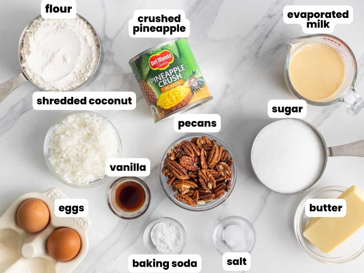 The ingredients for Do Nothing Cake, measured into small bowls, arranged on a marble counter.