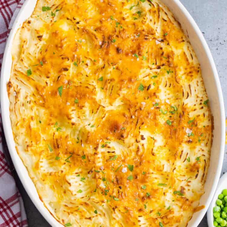 top down view of a potato topped fish stew pie in an oval baking dish.