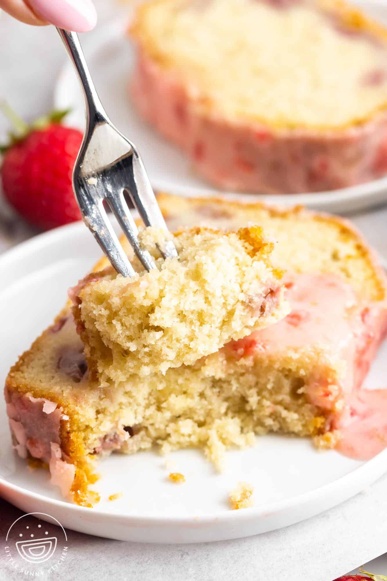 a three pronged fork taking a bite of strawberry pound cake.