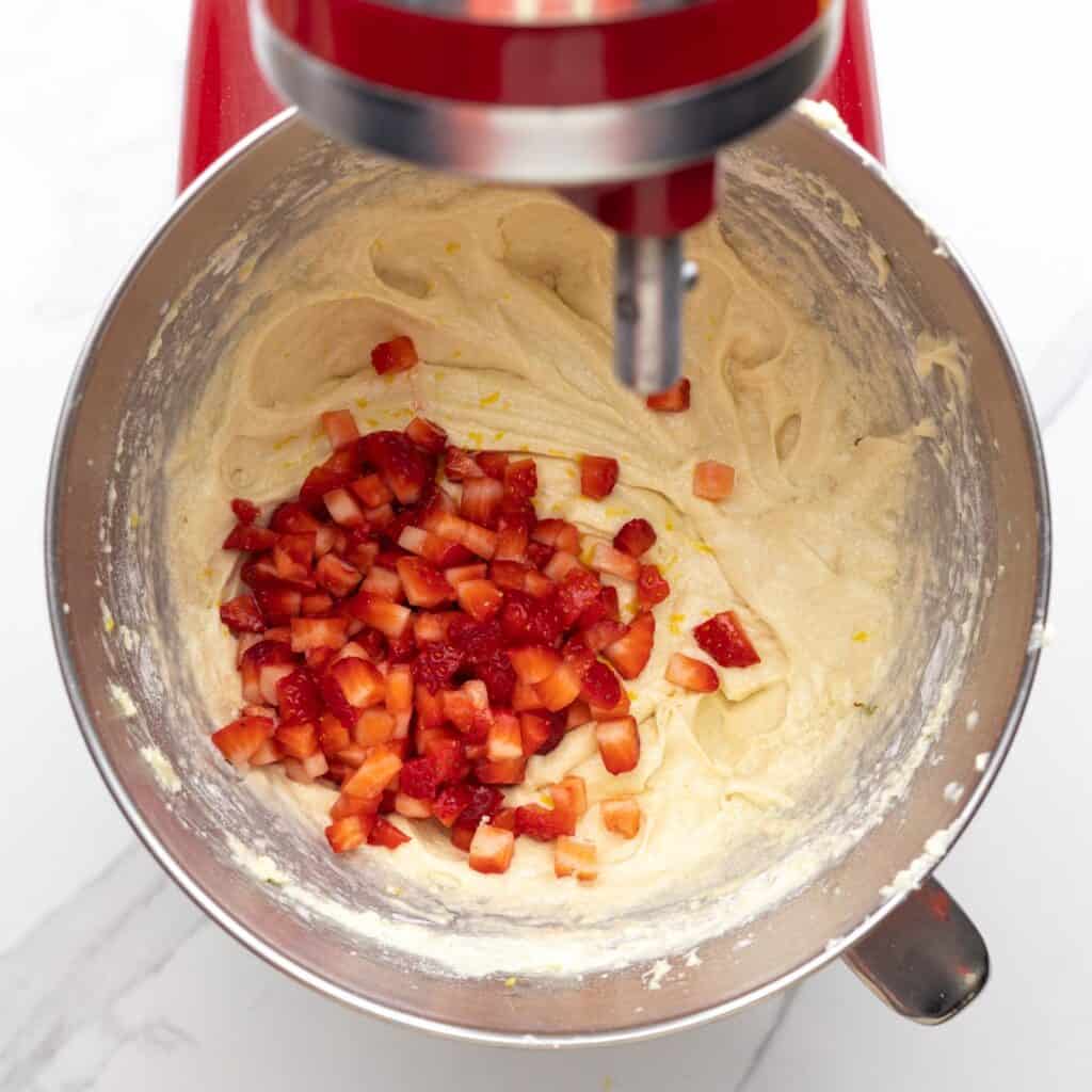 diced fresh strawberries added to pound cake batter in a mixing bowl.