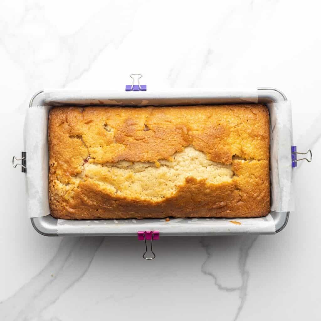 baked strawberry pound cake in a loaf pan lined with parchment paper.