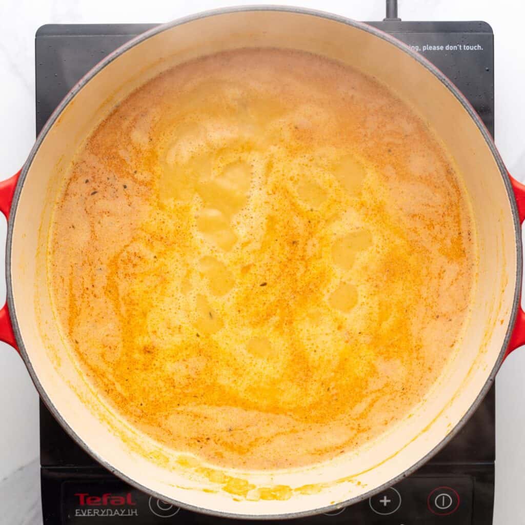 Thai curry chicken soup simmering in a dutch oven, viewed from overhead.