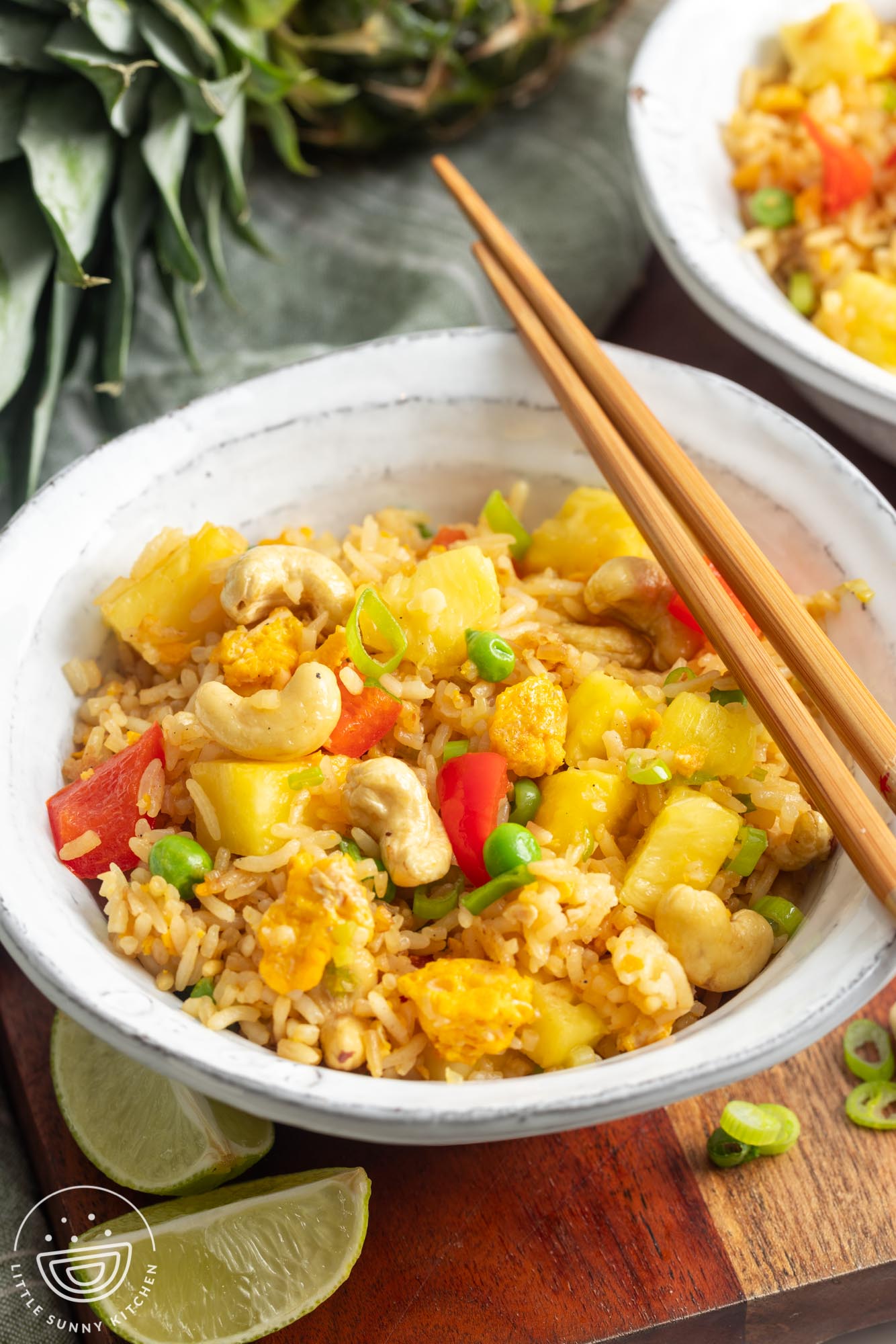 a serving bowl filled with Thai pineapple fried rice. wooden chopsticks are resting on the edge of the bowl.