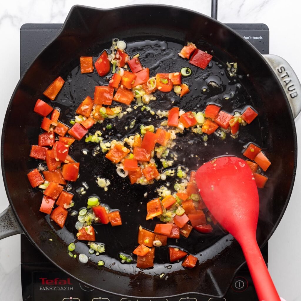 garlic, green onion, and red peppers in a cast iron skillet.