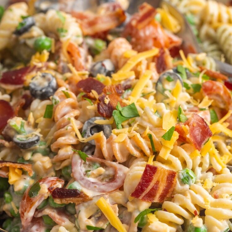 bacon ranch pasta salad with olives and peas in a serving bowl.