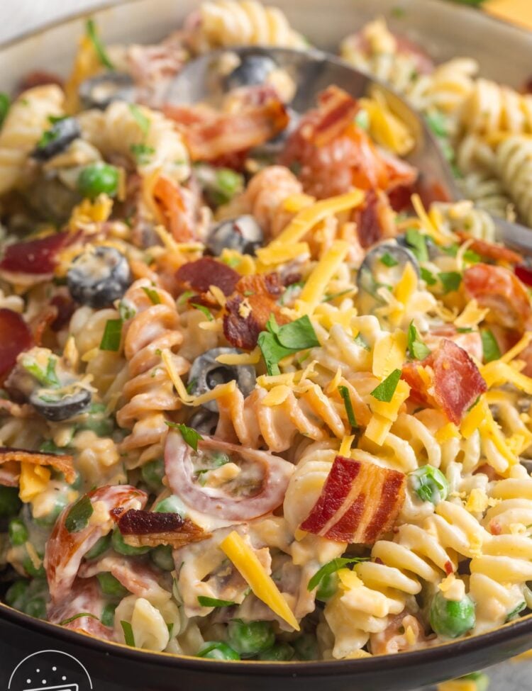 bacon ranch pasta salad with olives and peas in a serving bowl.