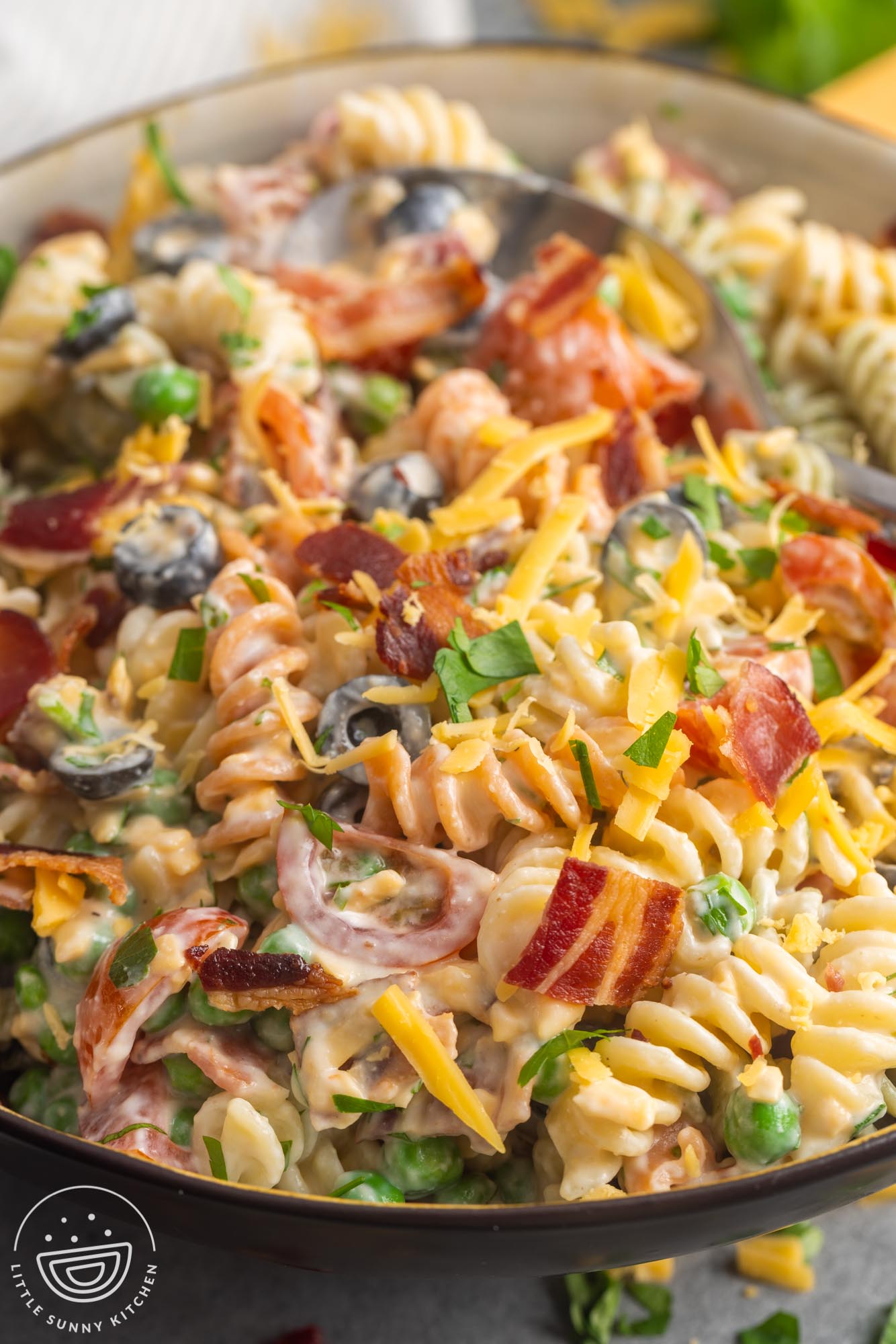 bacon ranch pasta salad with olives and peas in a serving bowl.