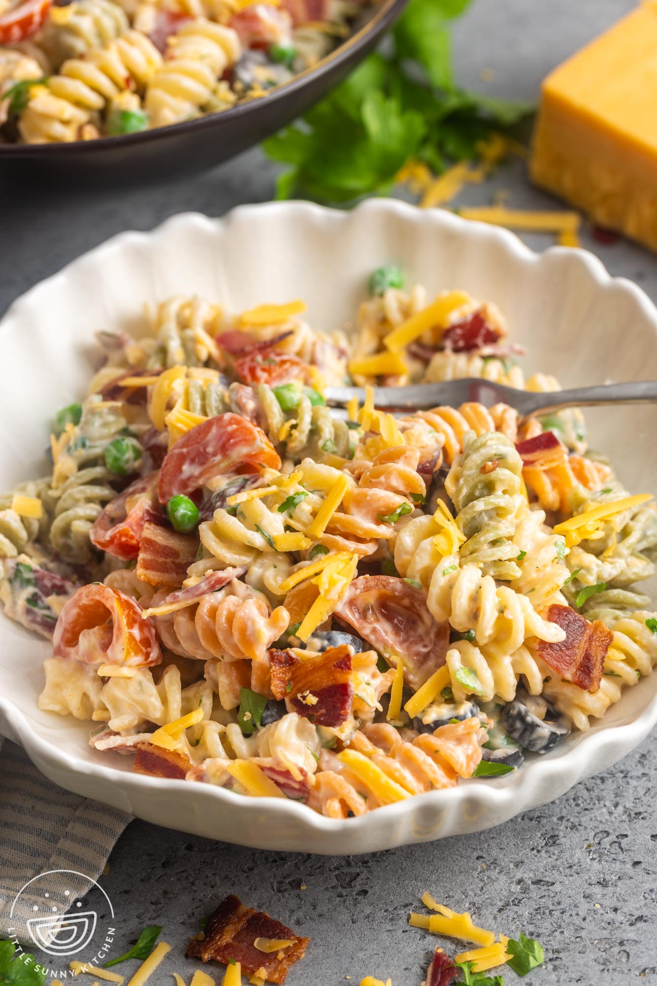 a serving of ranch pasta salad in a white textured bowl with a fork.