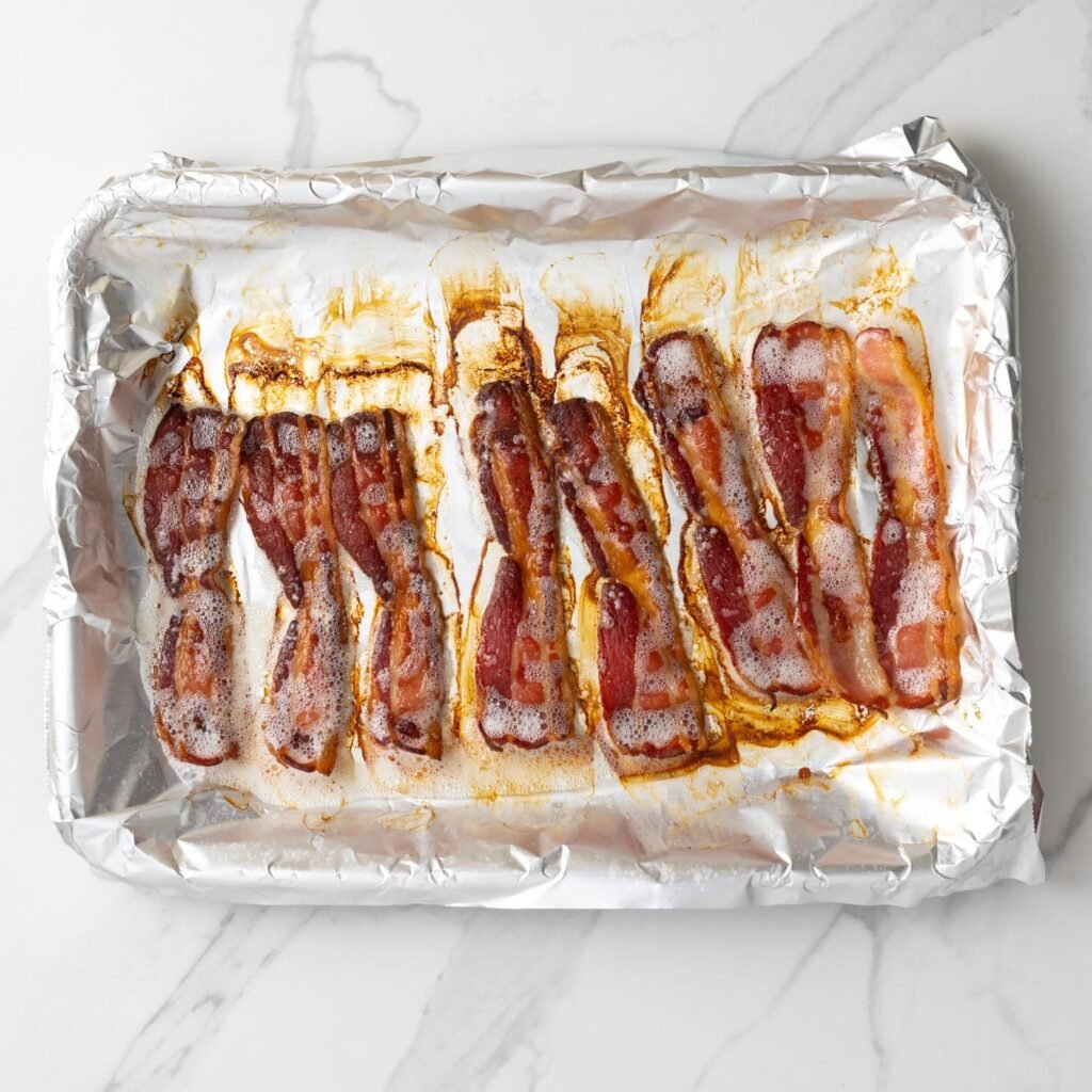 crispy baked bacon on an aluminum foil-lined baking sheet.