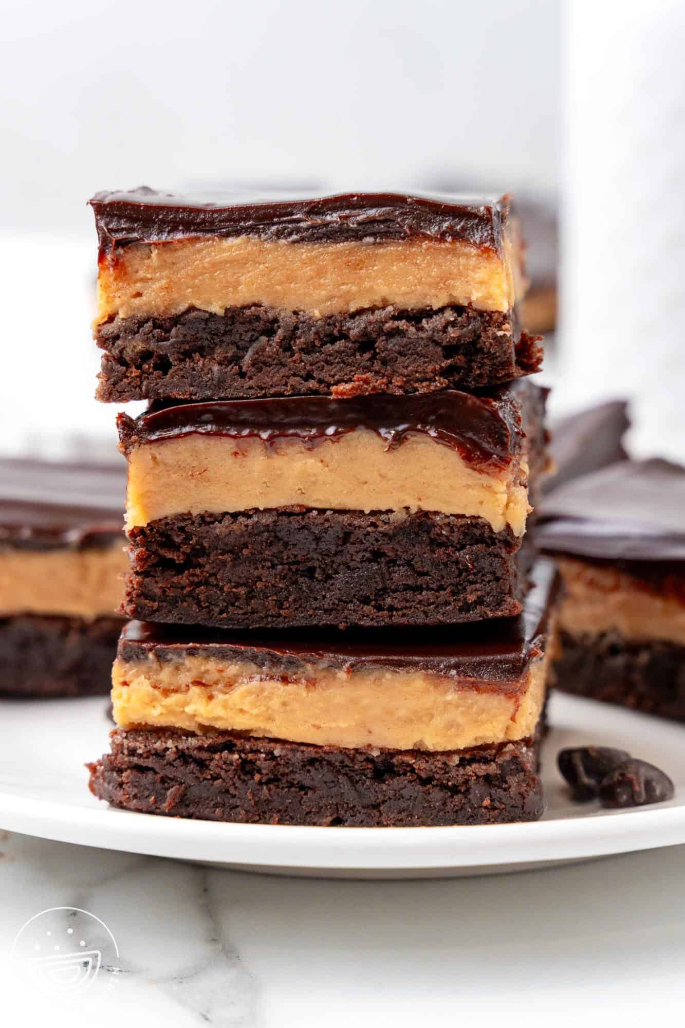 three layered buckeye brownies stacked on top of each other on a white plate.