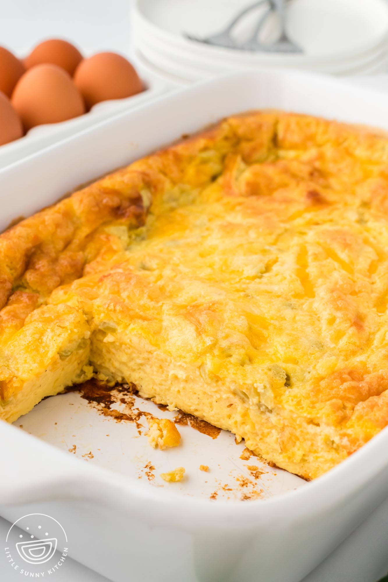 Green chili egg casserole in a white baking dish. Two squares have been removed.