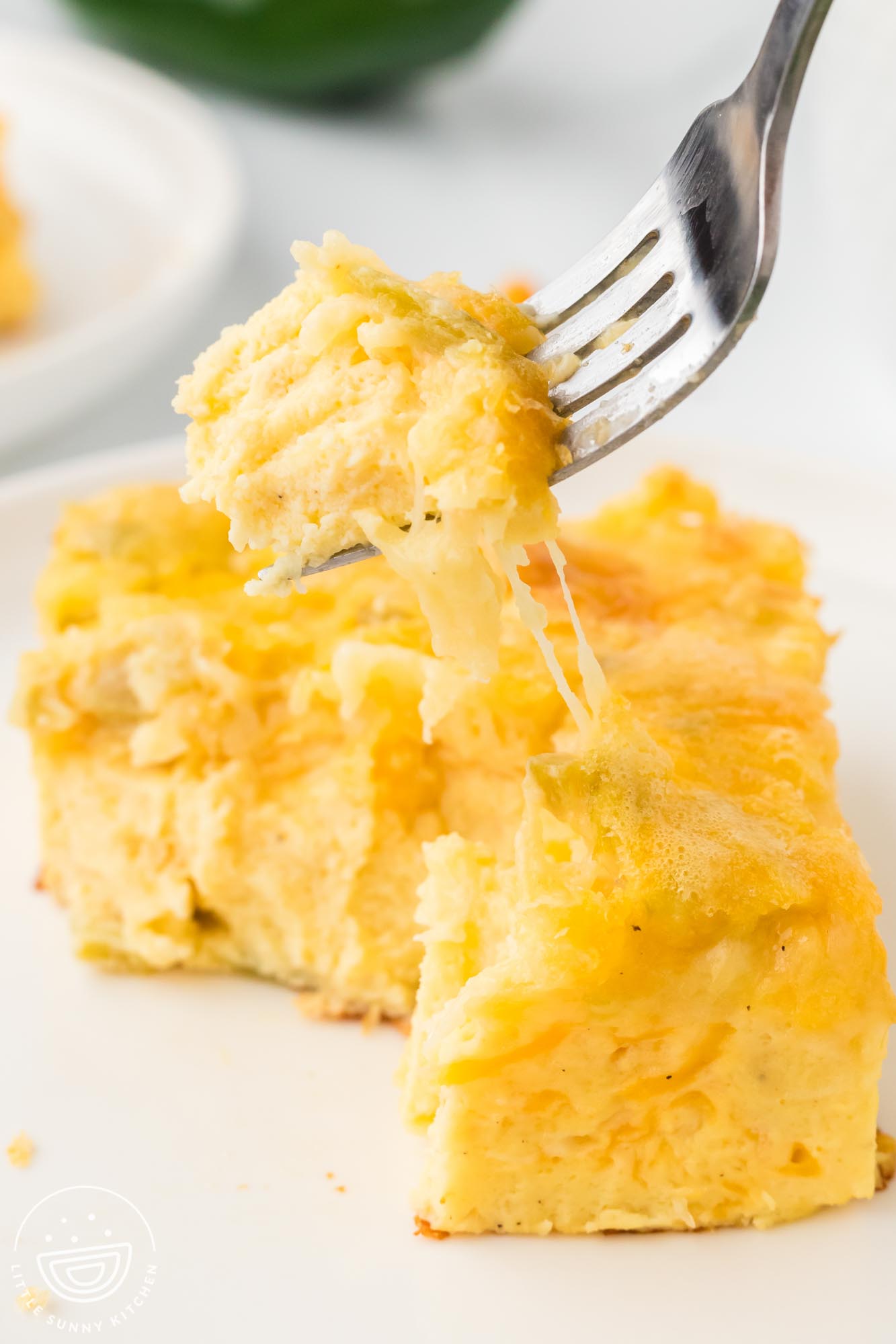 a fork eating a piece of green chili egg casserole with melty cheese.